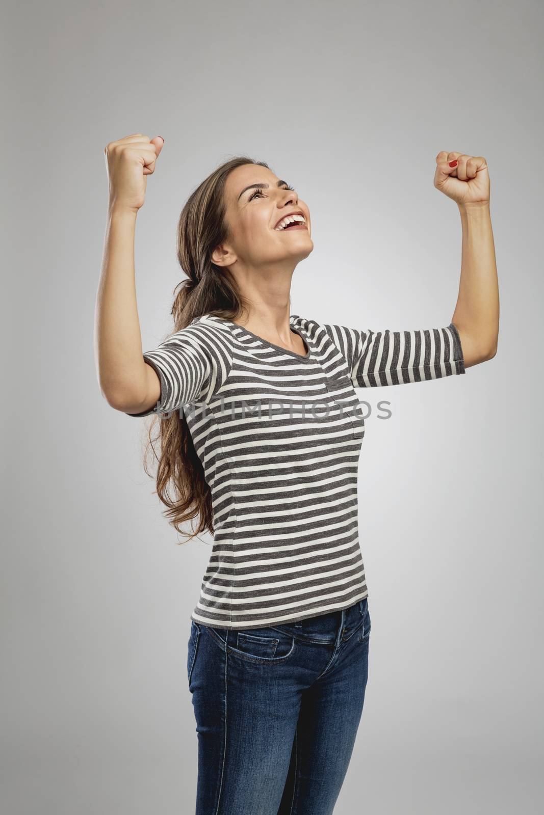 Portrait of a beautiful happy woman with arms raised and looking up