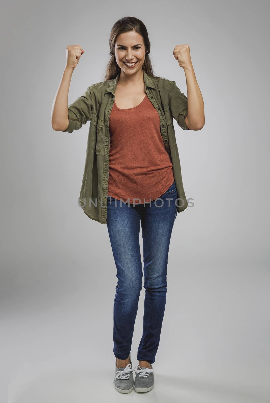 Beautiful and successful young woman with arms raised