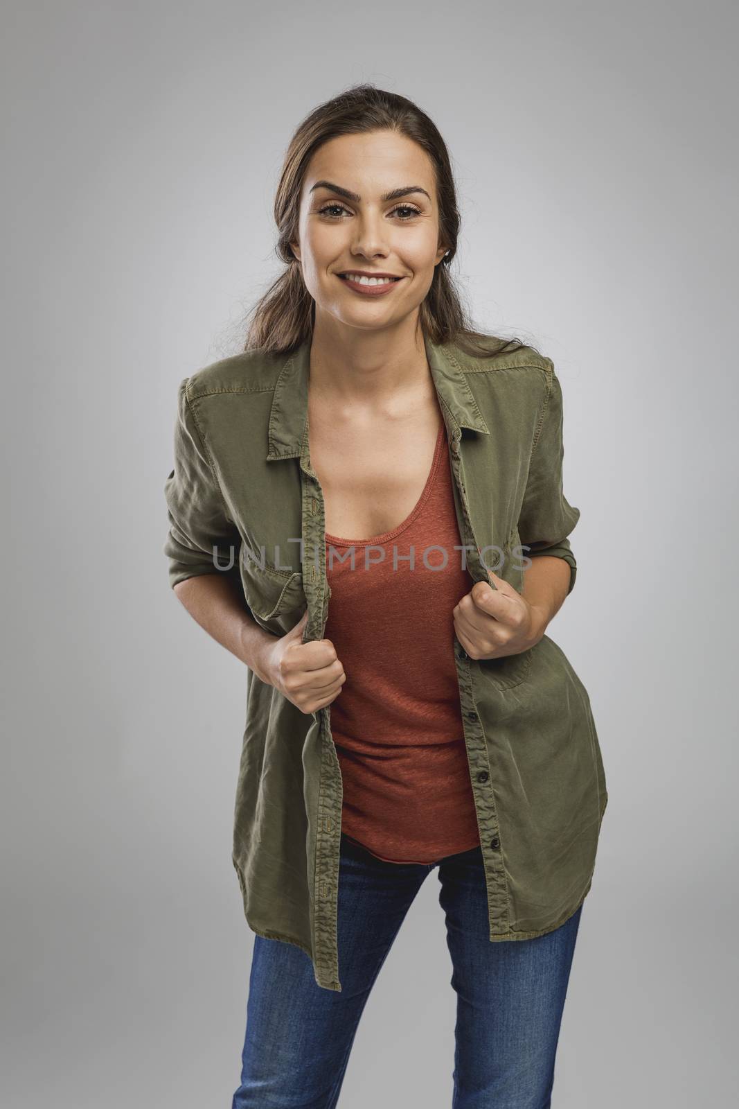 Beautiful young woman standing over a gray background and smiling