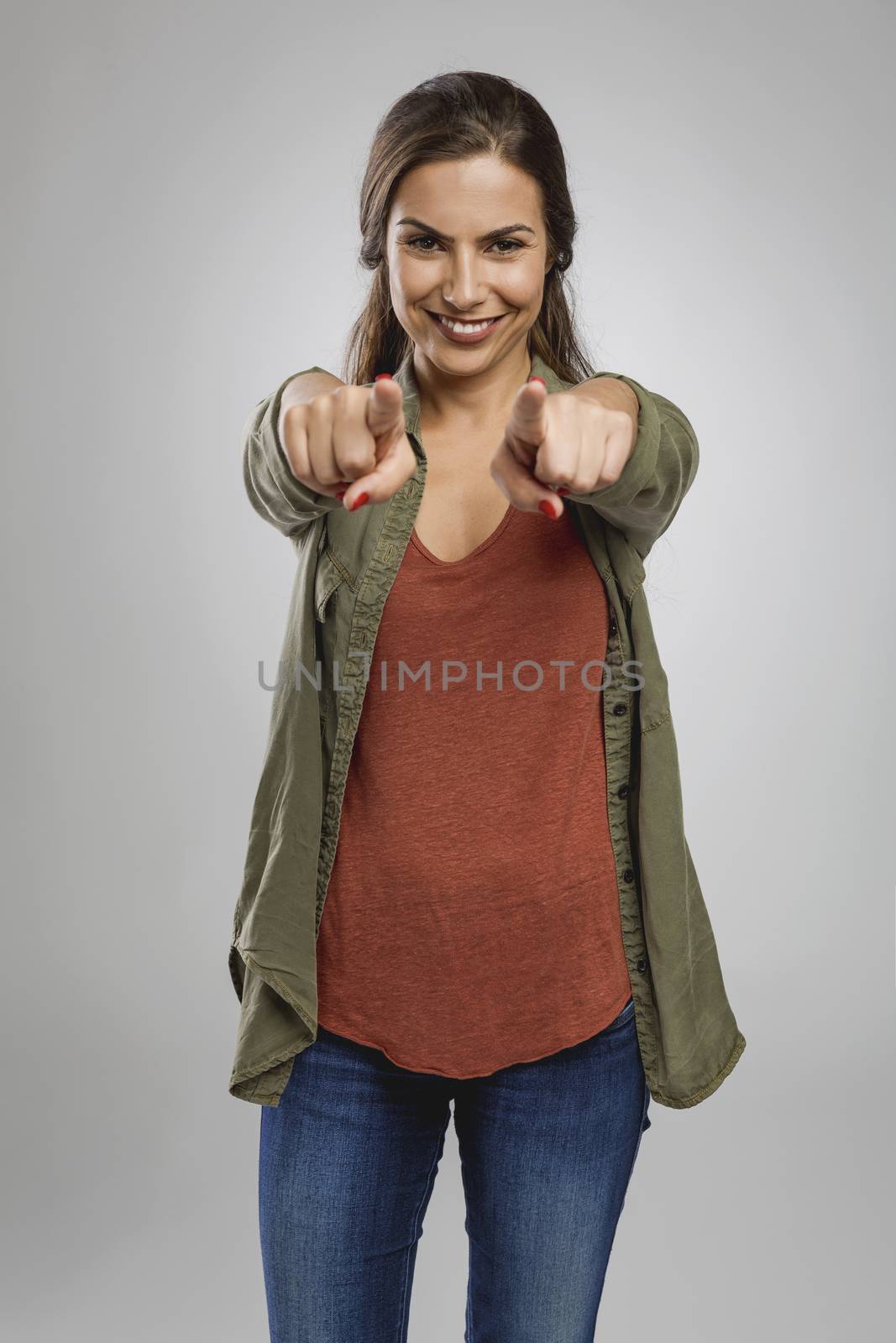 Beautiful happy woman looking and pointing with both arms to the camera