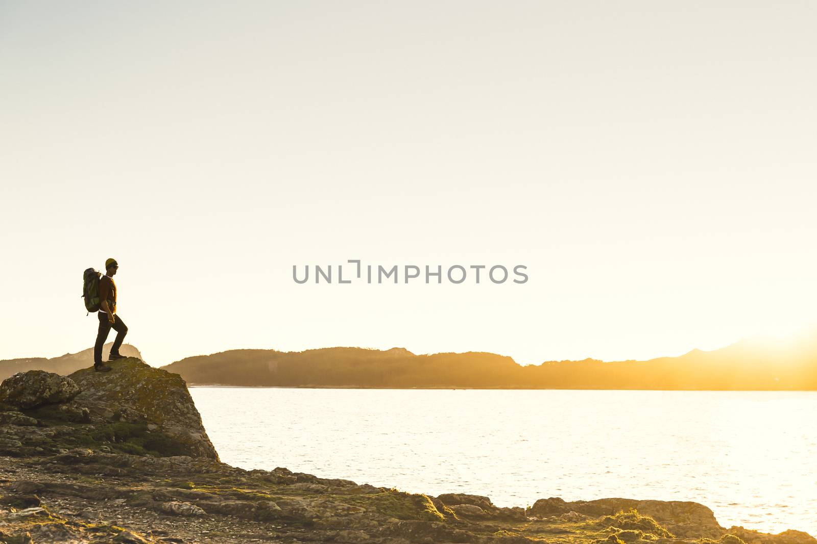 Shot of a man enjoying the view of the coast at sunset