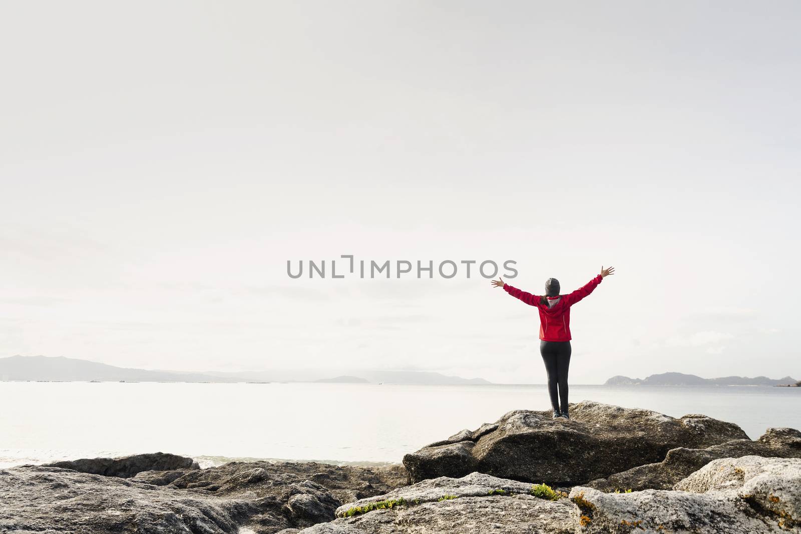Woman with arms raised  enjoying the beautiful morning view of the coast