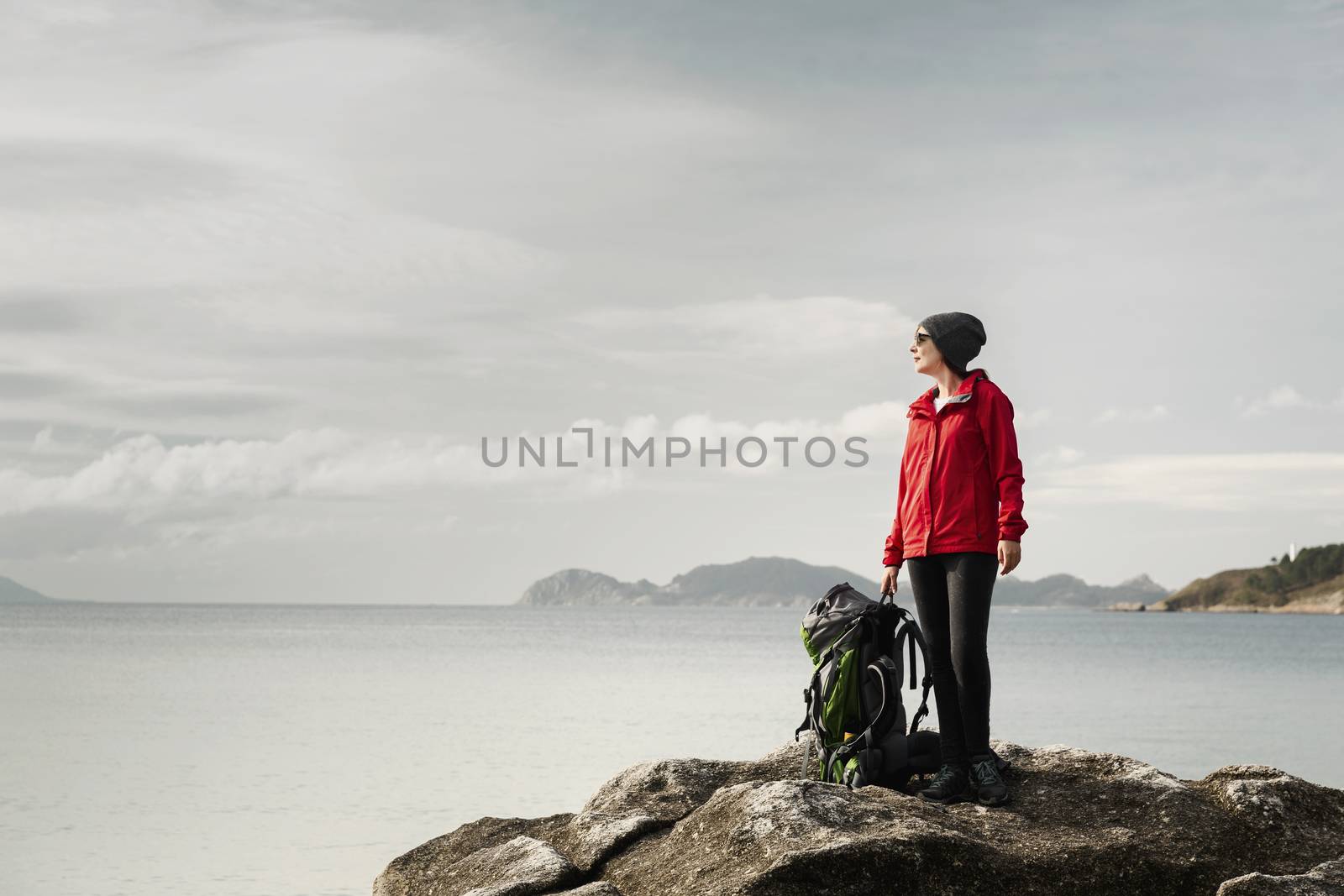 Woman with backoack enjoying the morning view of the coast