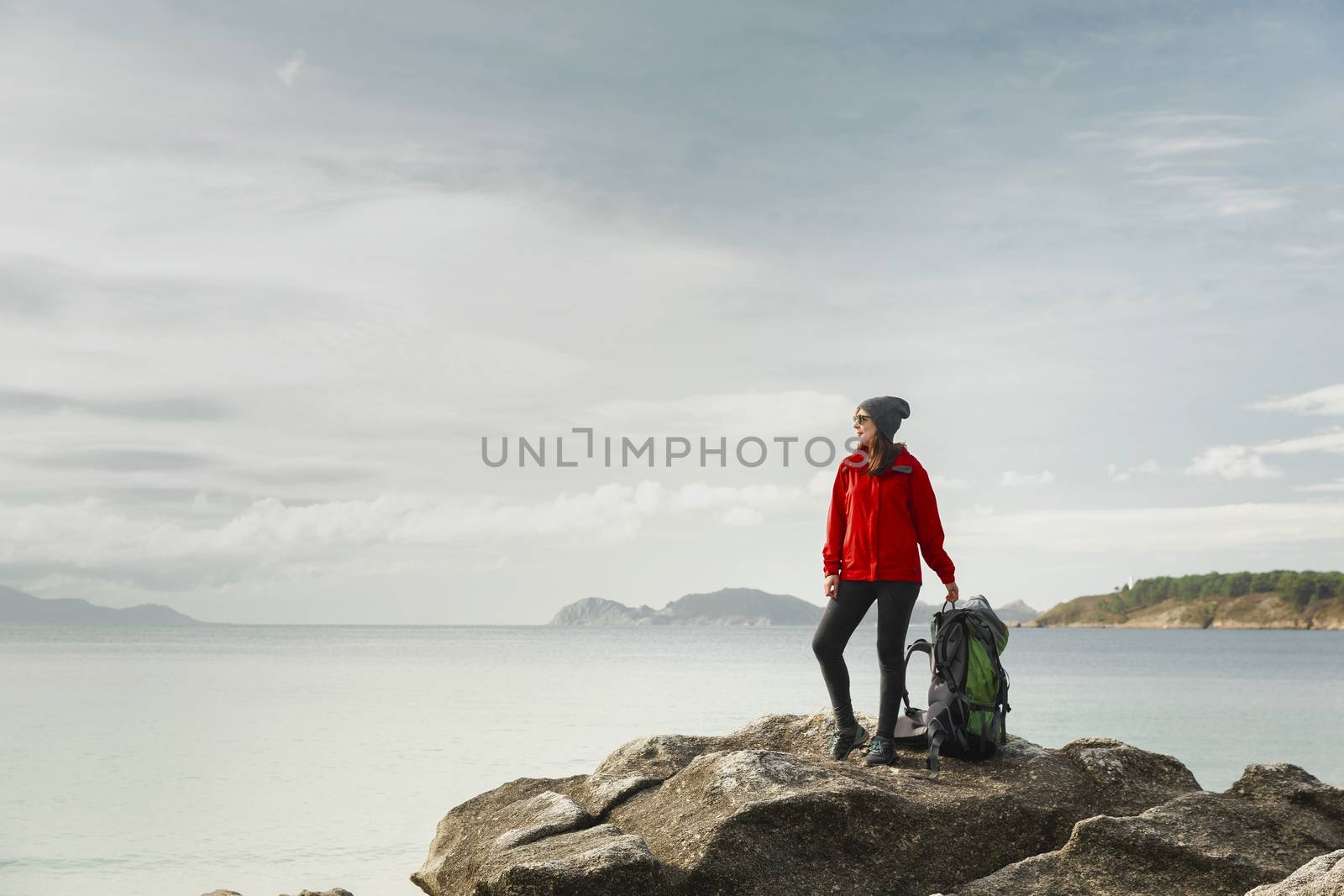 Woman with backoack enjoying the morning view of the coast