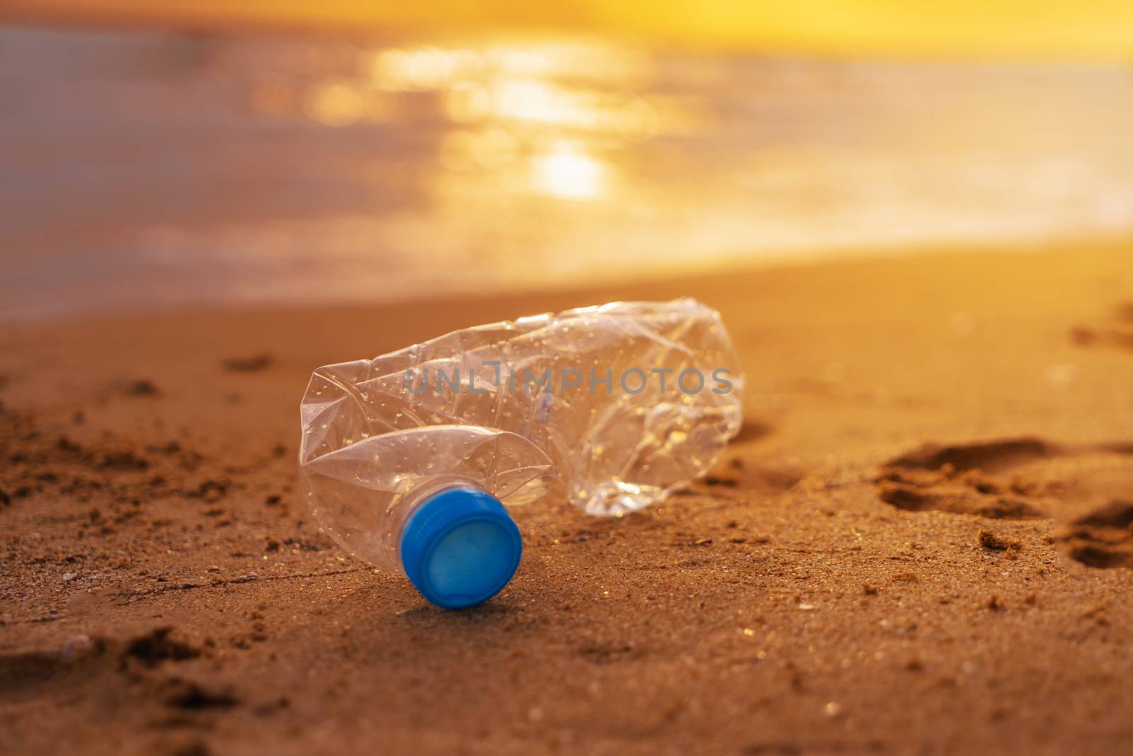 The plastic bottle  on the beach at the sunset, keep clean up the beach