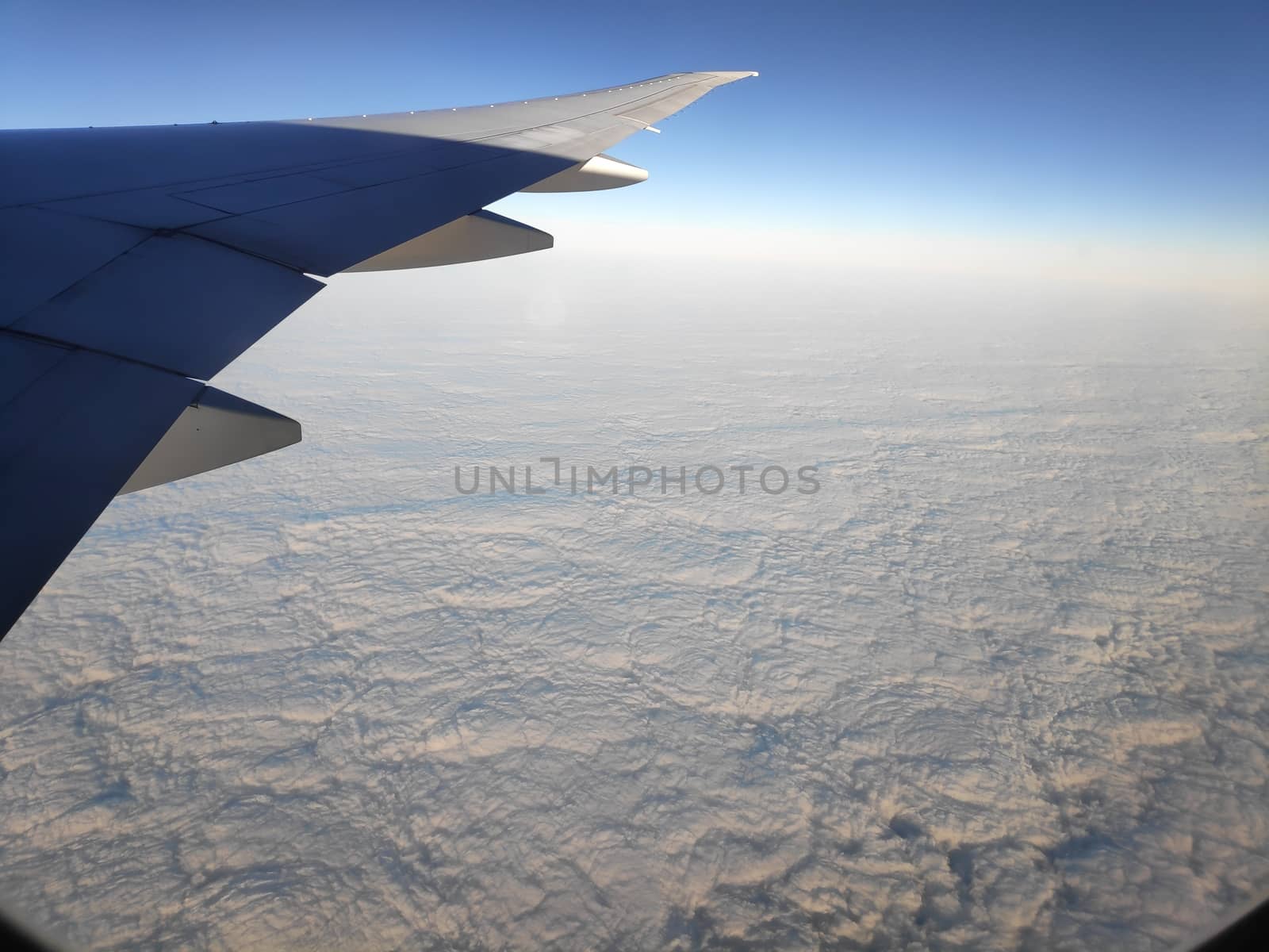 View outside plane window on closed cloud cover with wing