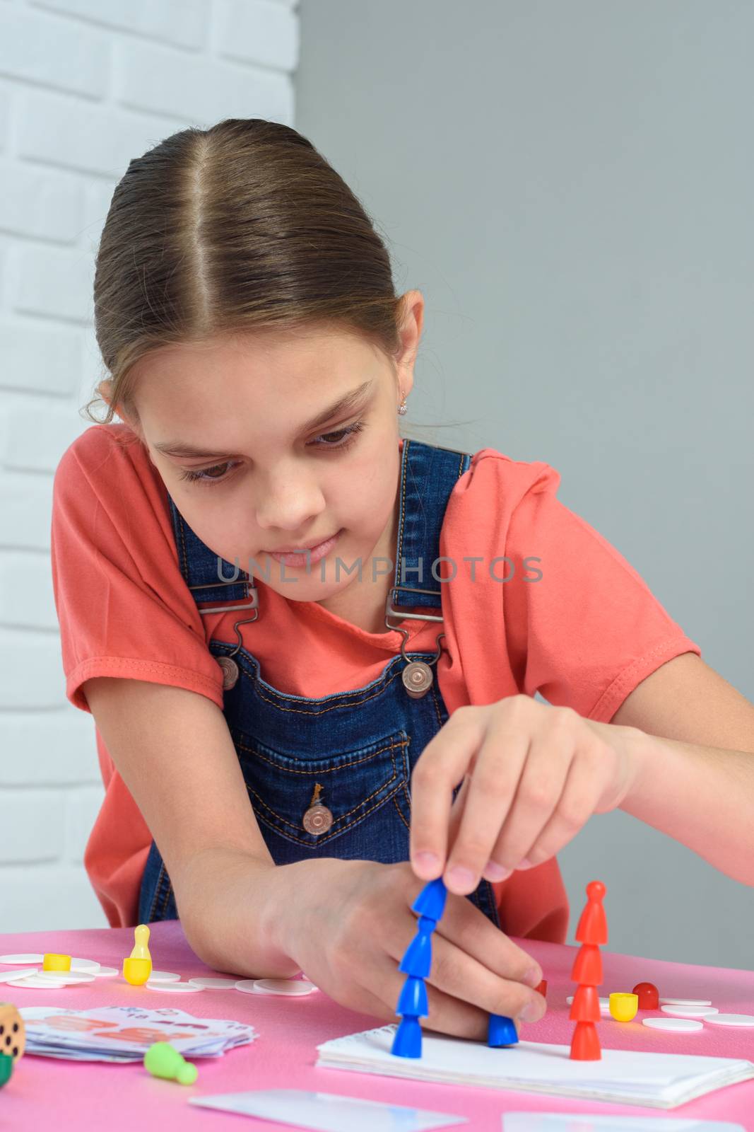 Girl enthusiastically puts chips on each other while playing a board game by Madhourse