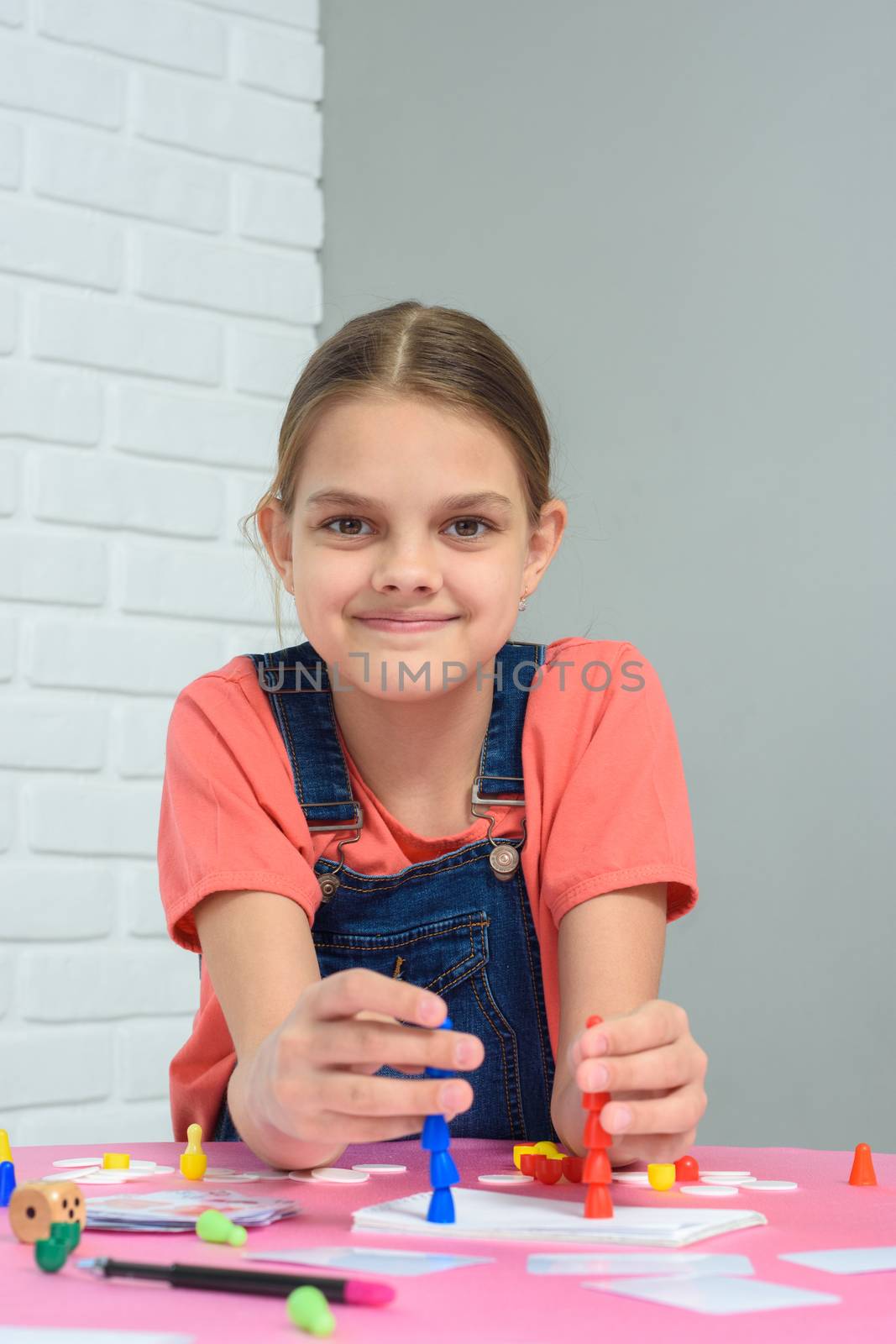 Girl plays board games, sits at a table at home
