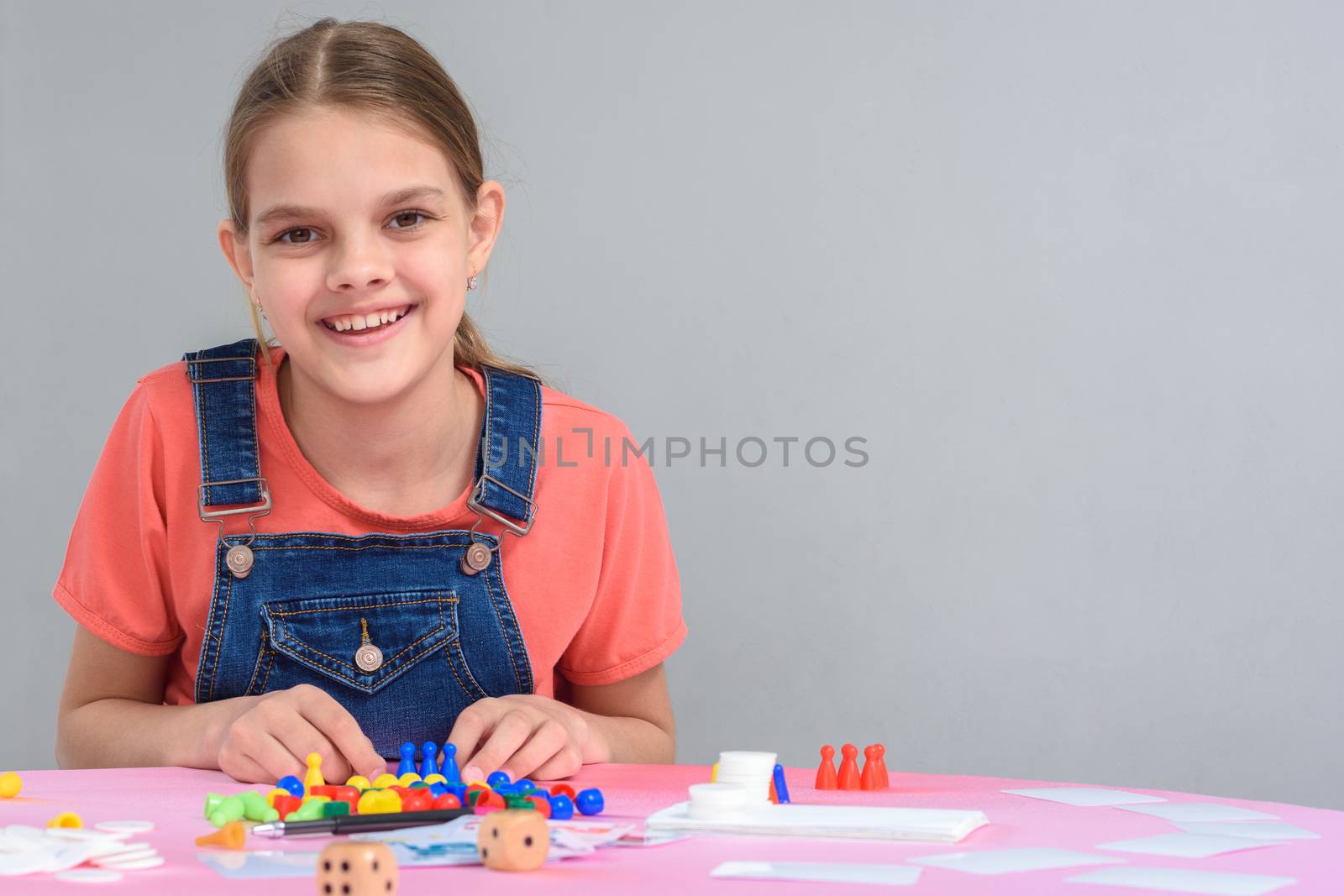 Girl sitting at the table playing board games, free space on the right