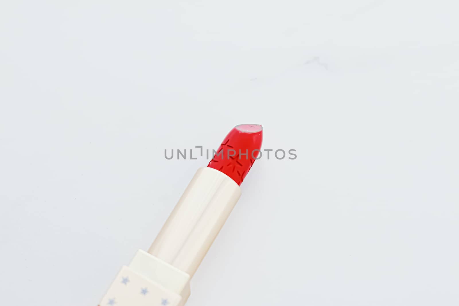 Luxury lipstick in a golden tube on white marble background, make-up and cosmetics concept