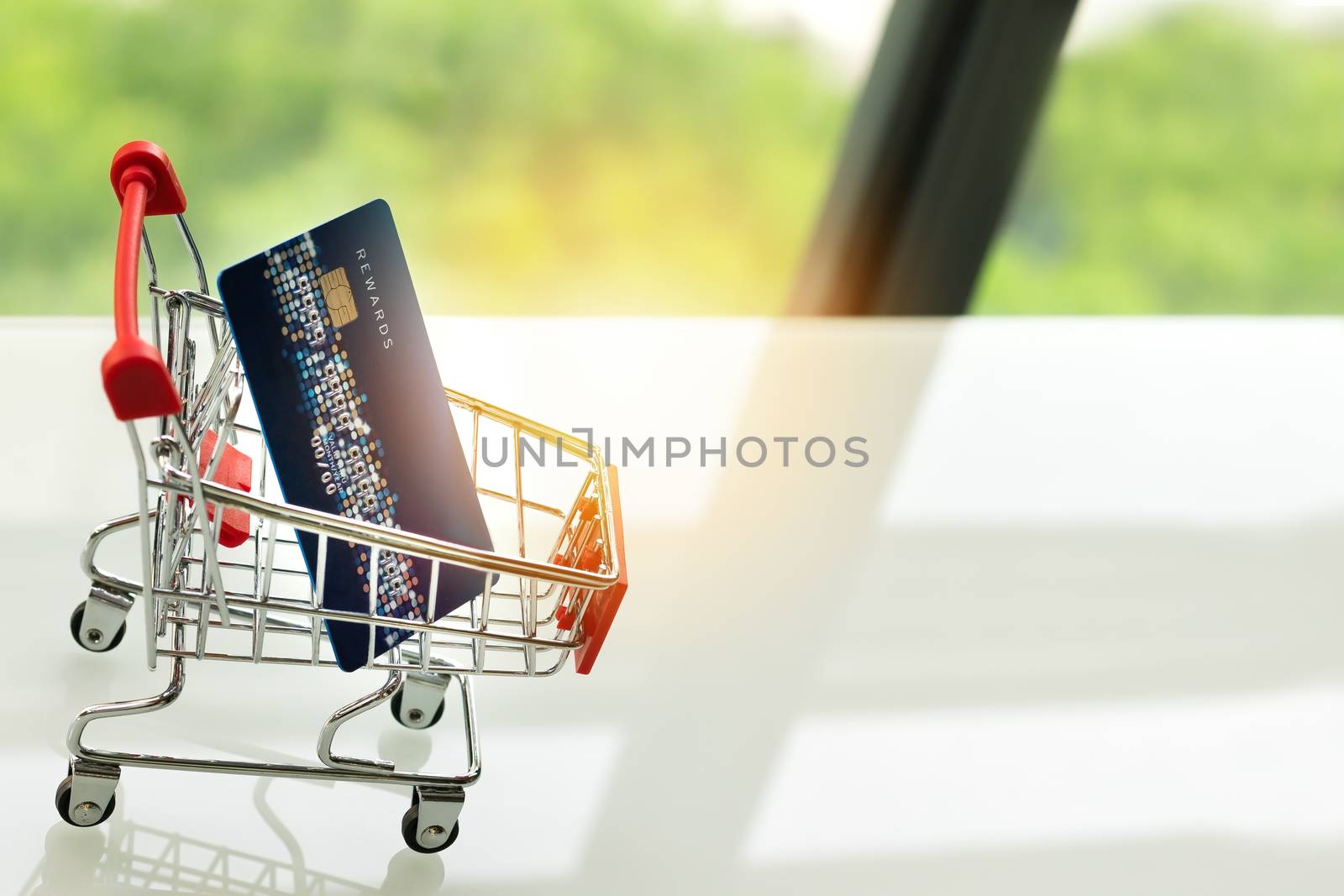 credit card on shopping cart trolley on white table with green backgrounds