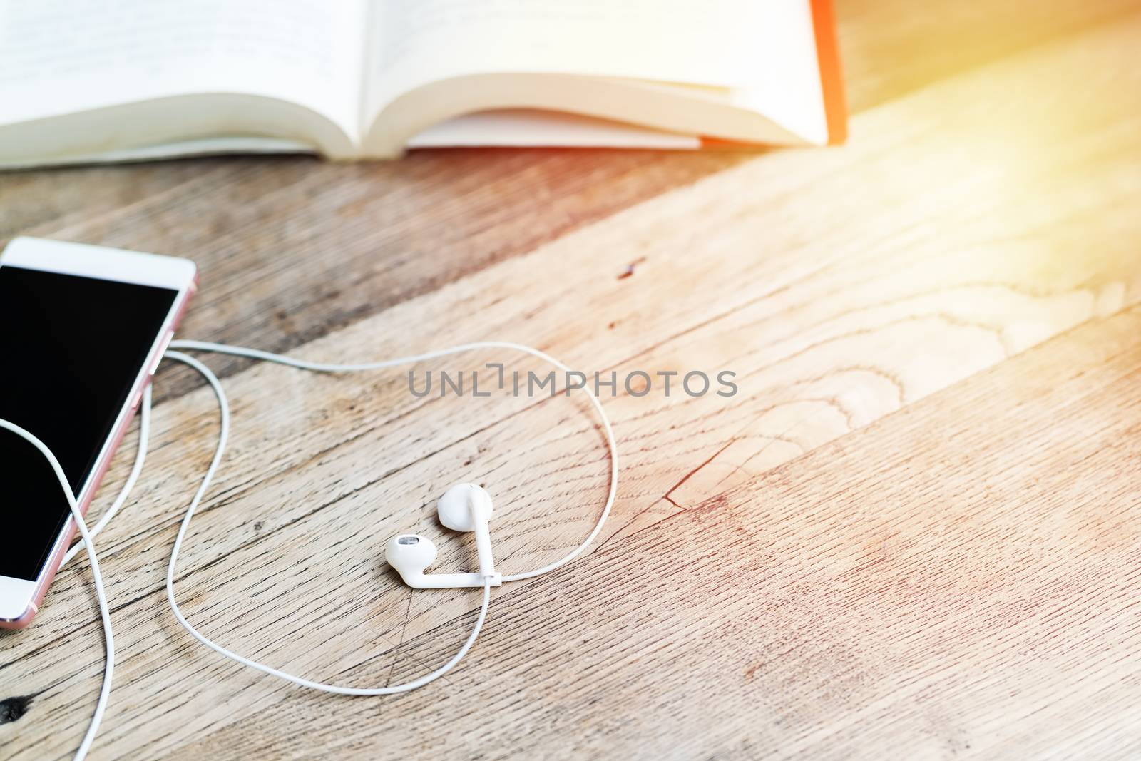 white heart shape earphone with smartphone and open book on work by psodaz