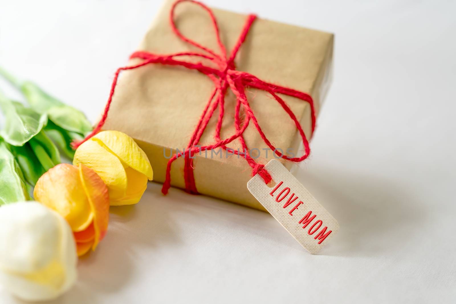 Happy mother's day concept. Gift box and flower, paper tag with LOVE MOM text