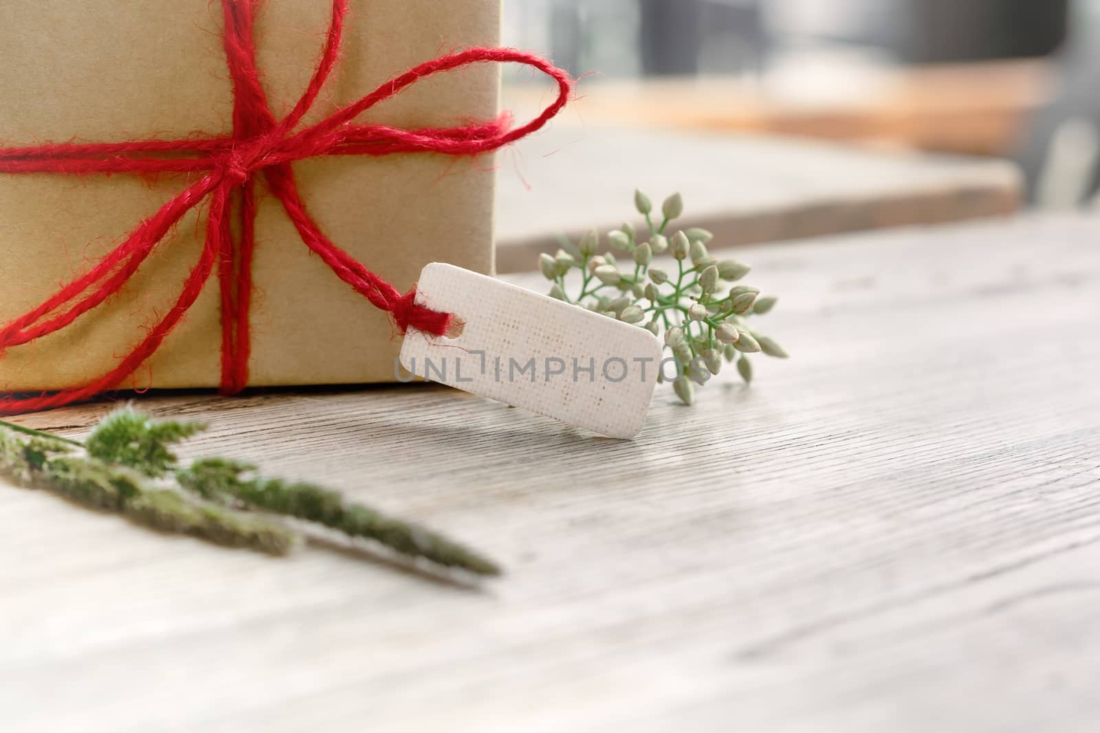 Gift box with blank tag and flower on wooden table, copy space for texting