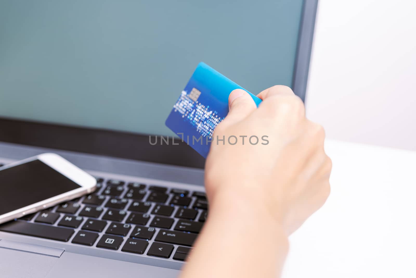 Hands holding credit card and using smart phone and laptop. Online shopping