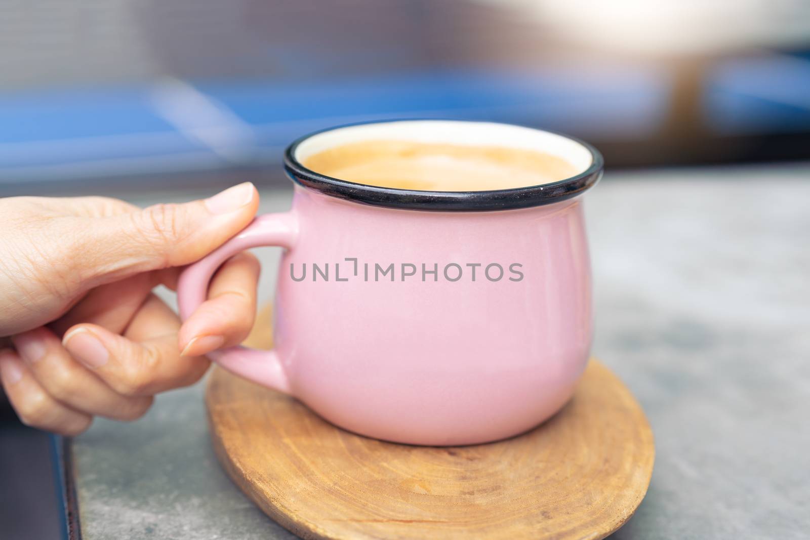 women hand touch pink cup of hot coffee on wooden plate
