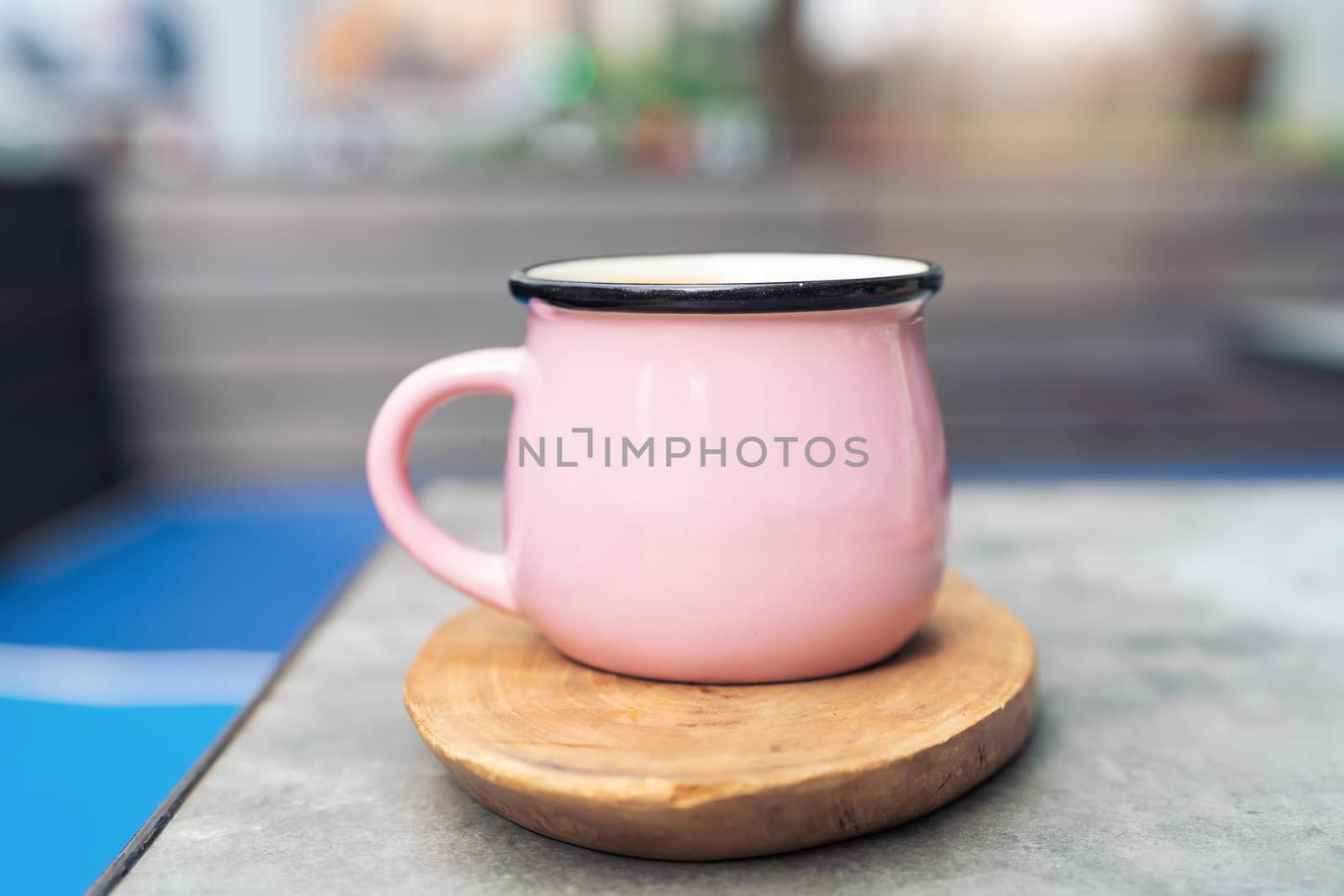 Coffee cup in pink glass on wooden plate