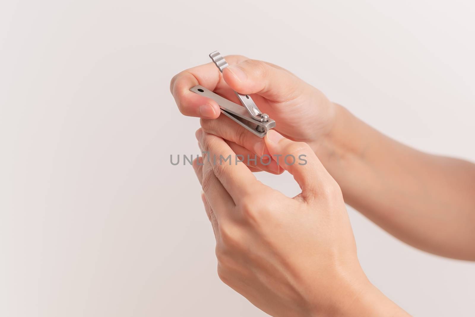 woman hand cutting nails using nail clipper on white backgrounds by psodaz