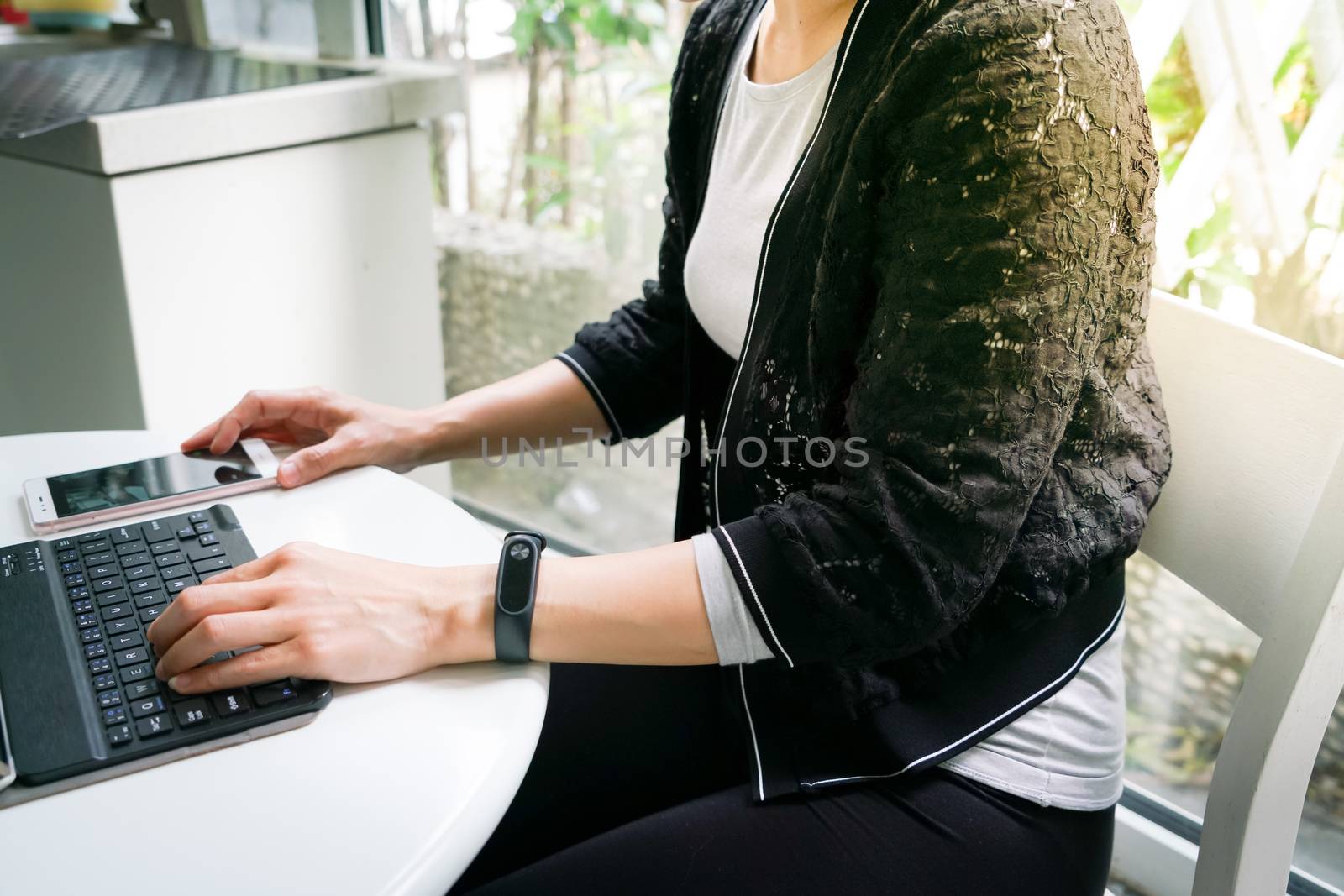 Young student women wearing smart band focus on her tablet computer and smart phone