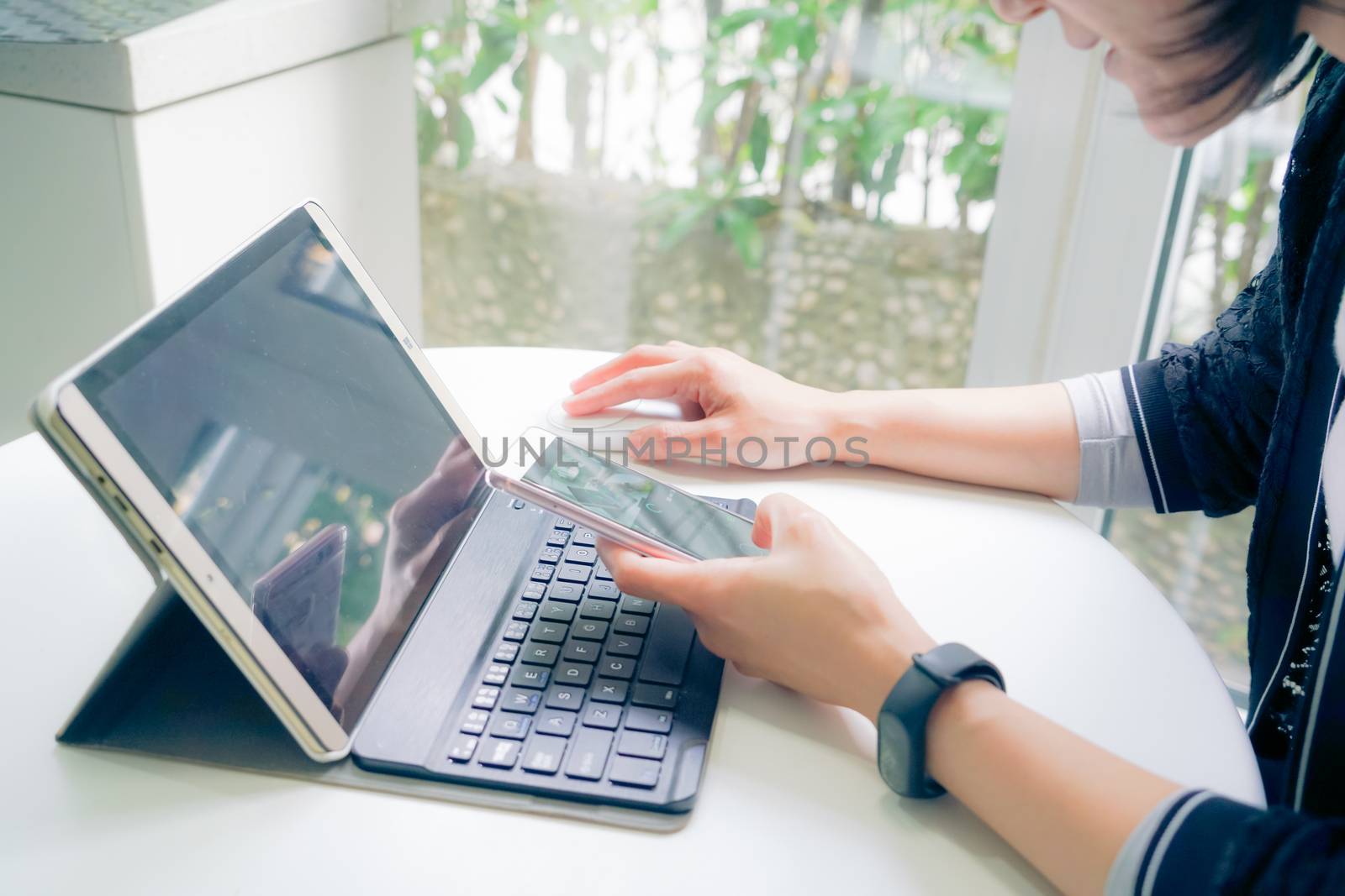 Young student women wearing smart band focus on her tablet computer and smart phone