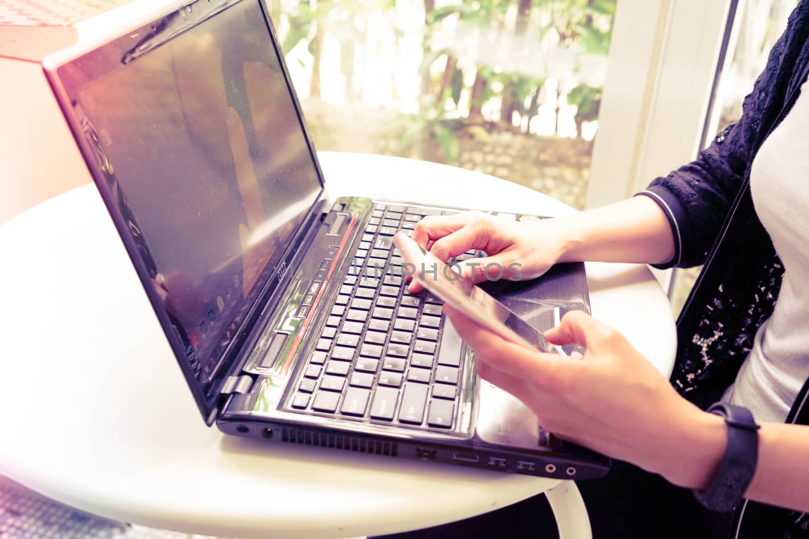 Young student women wearing smart band focus on her laptop computer and smart phone