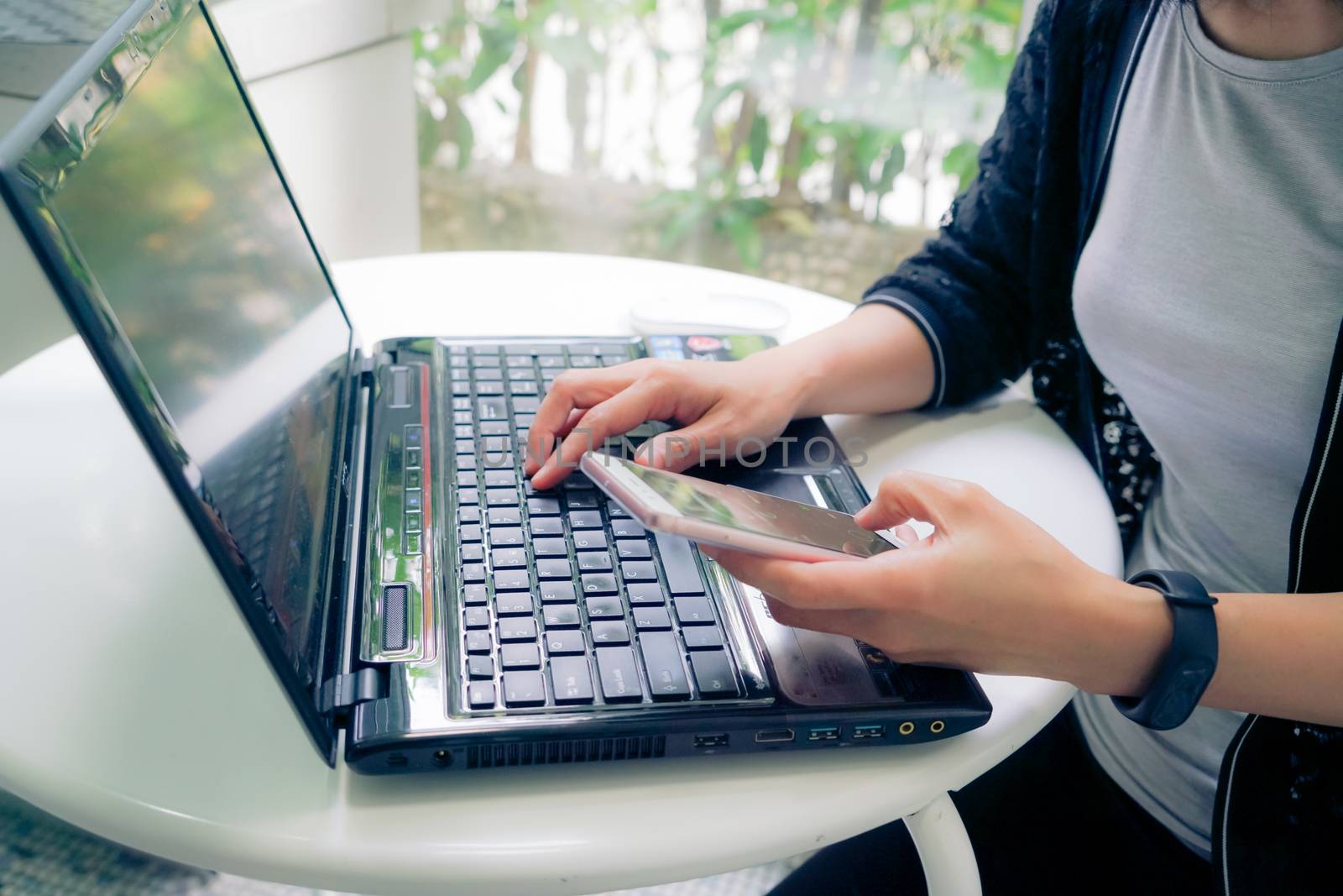 Young student women wearing smart band focus on her laptop computer and smart phone