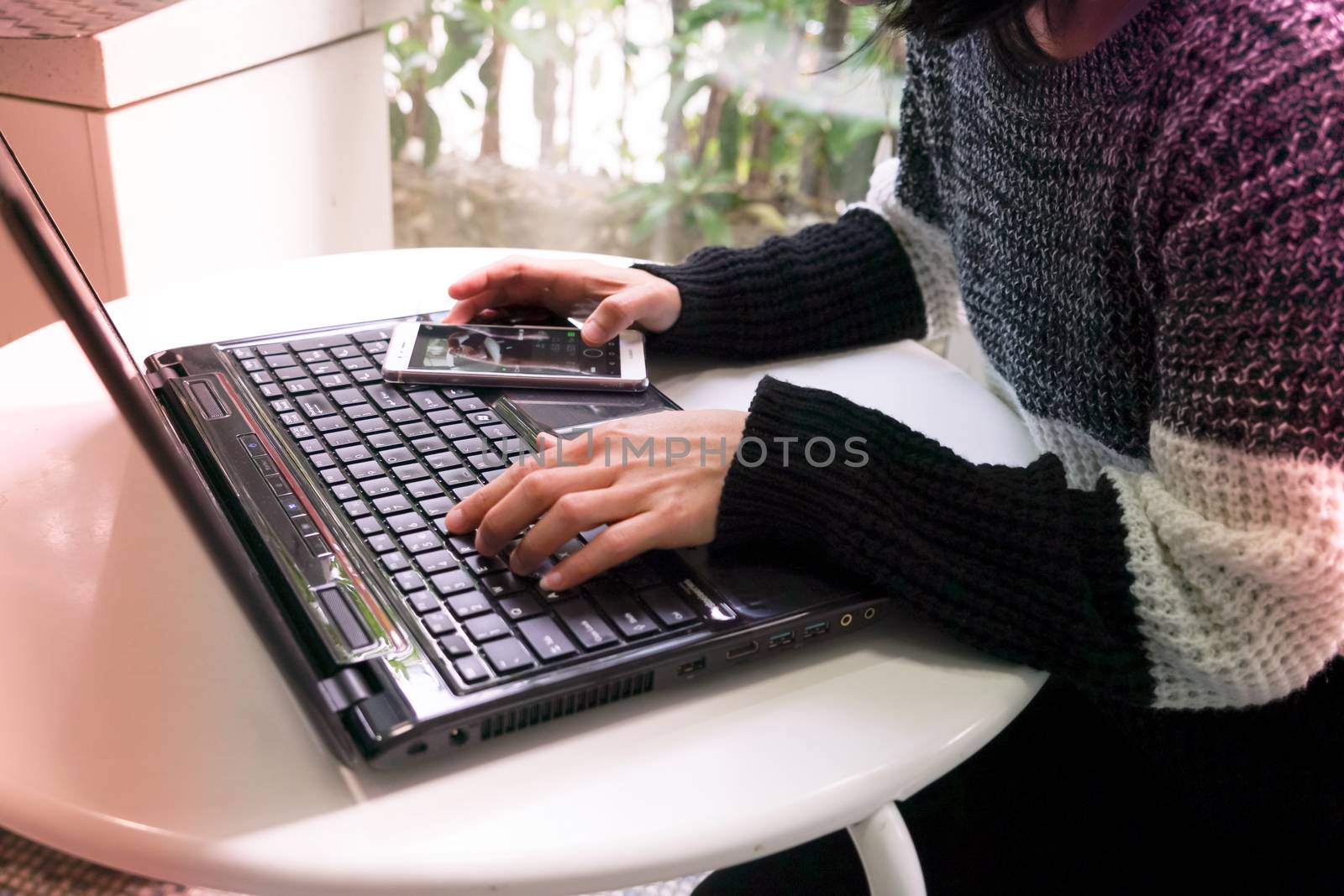 Young student women wearing smart band focus on her laptop computer and smart phone