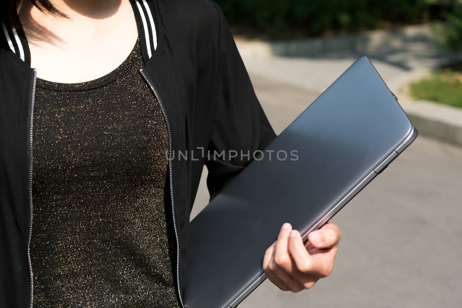 A student woman is holding laptop computer
