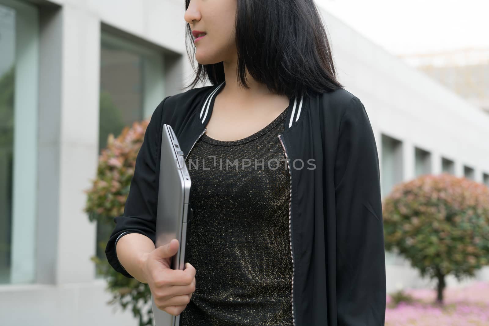 A woman is holding laptop computer while walking