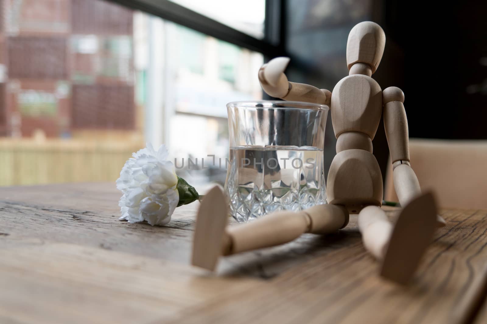 a wood man is sitting and put the arm on the glass of water