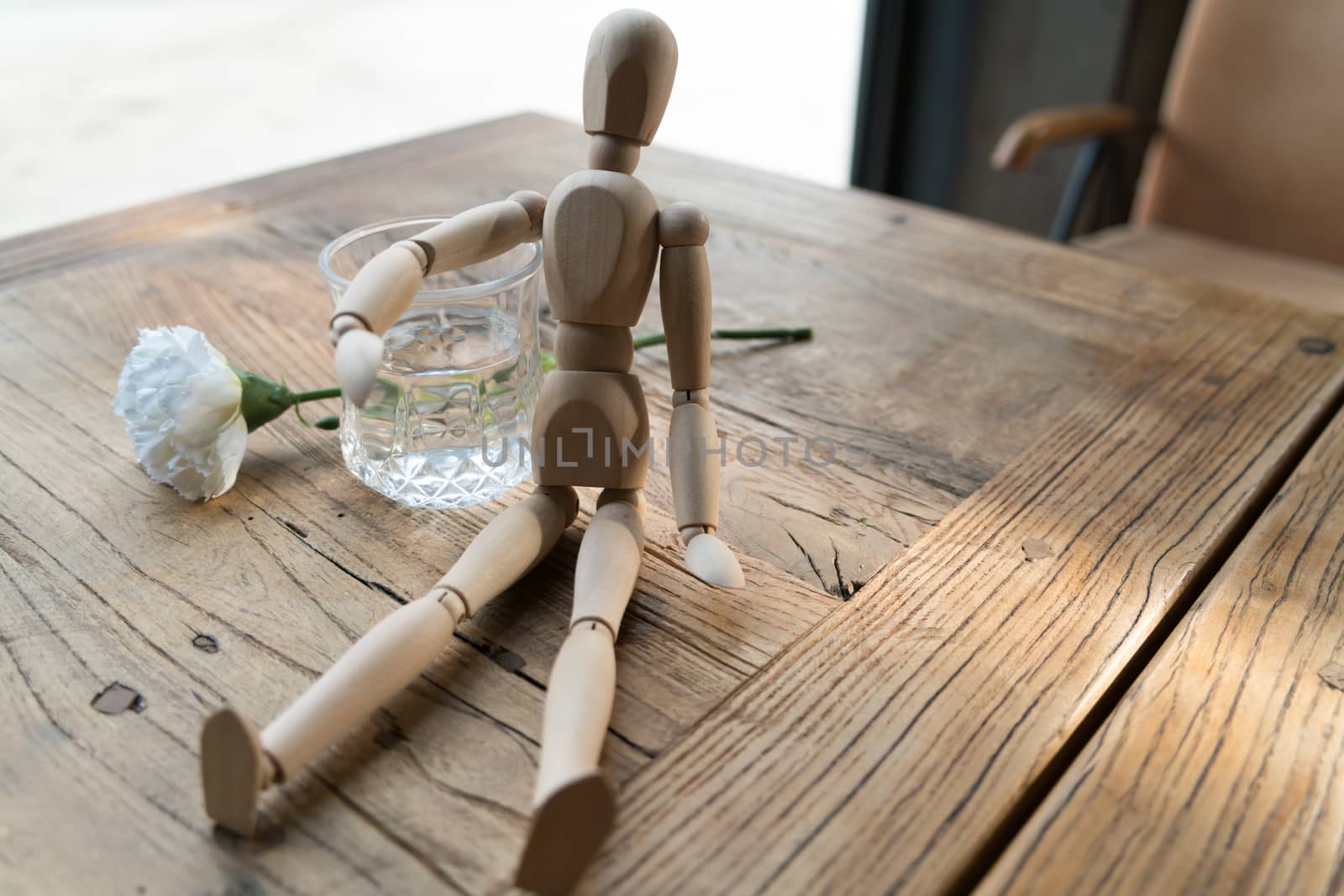 a wood man is sitting and put the arm on the glass of water