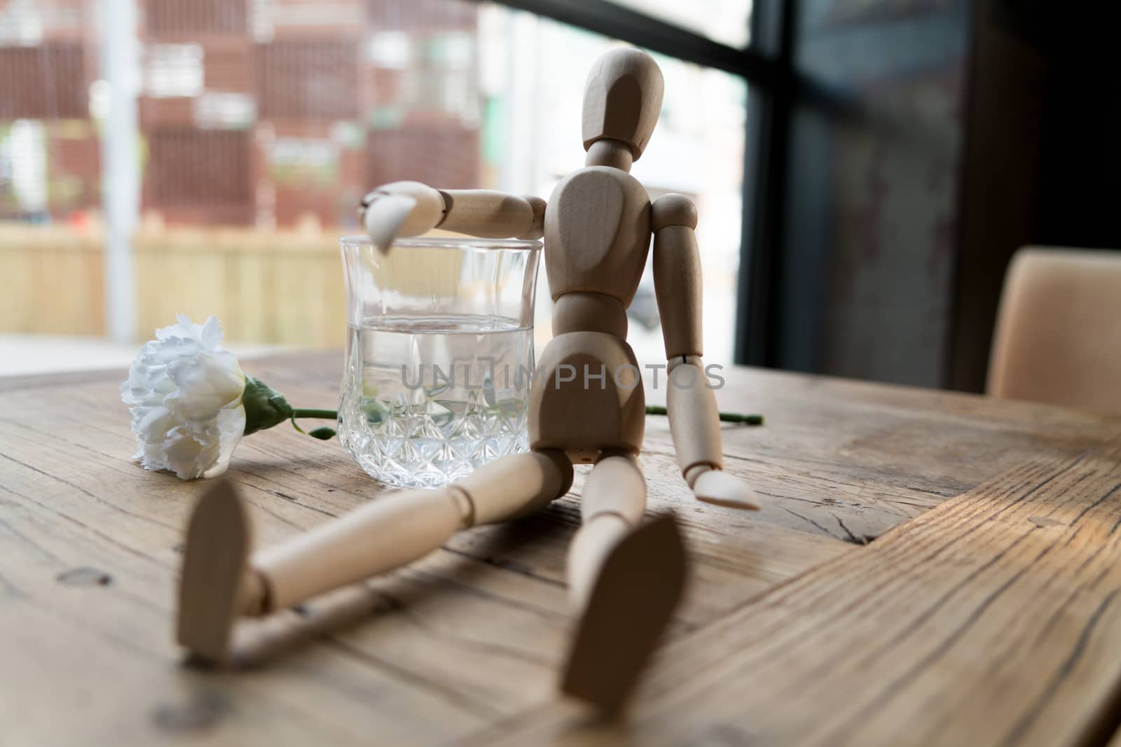 a wood man is sitting and put the arm on the glass of water by psodaz