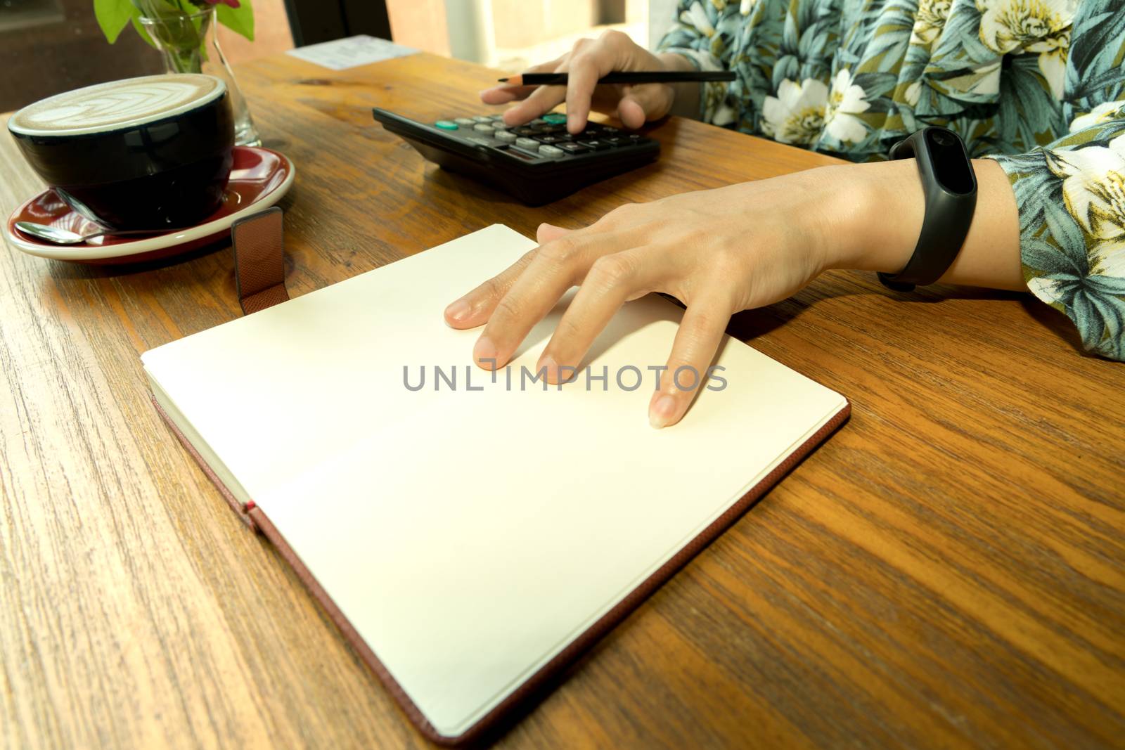 business women is calculating the expense on the wooden table with hot mocha coffee