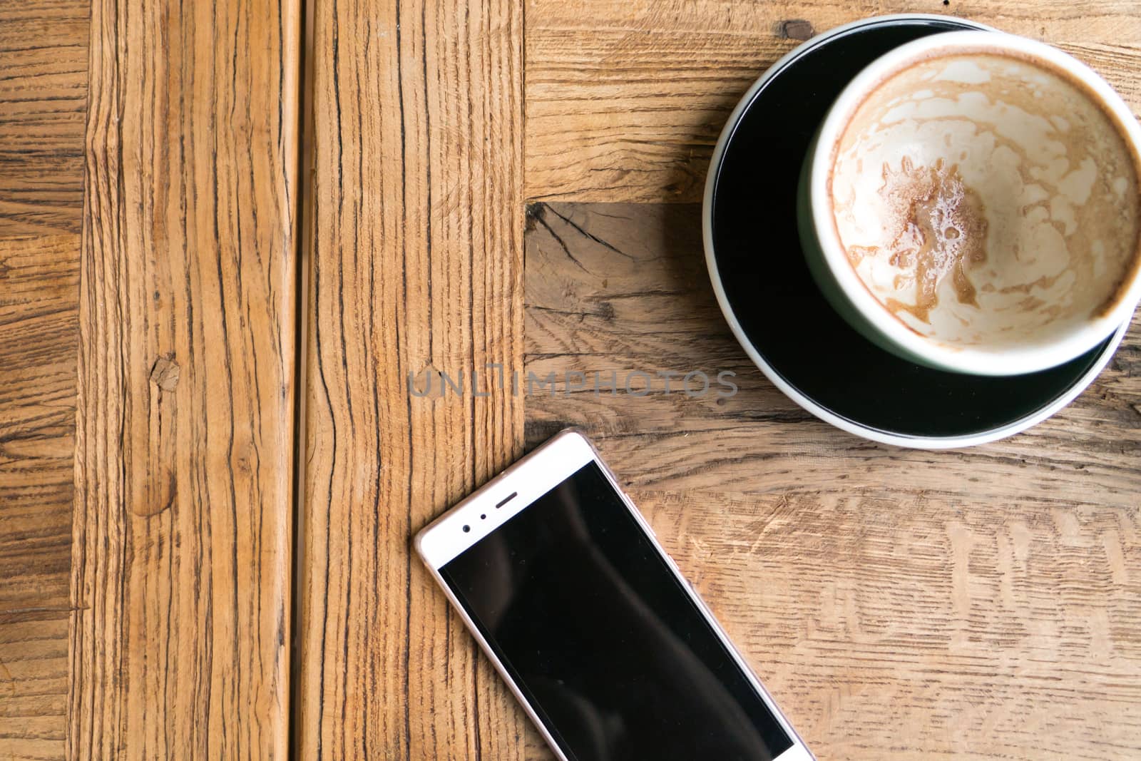 the empty coffee cup with the smart phone on the wooden table