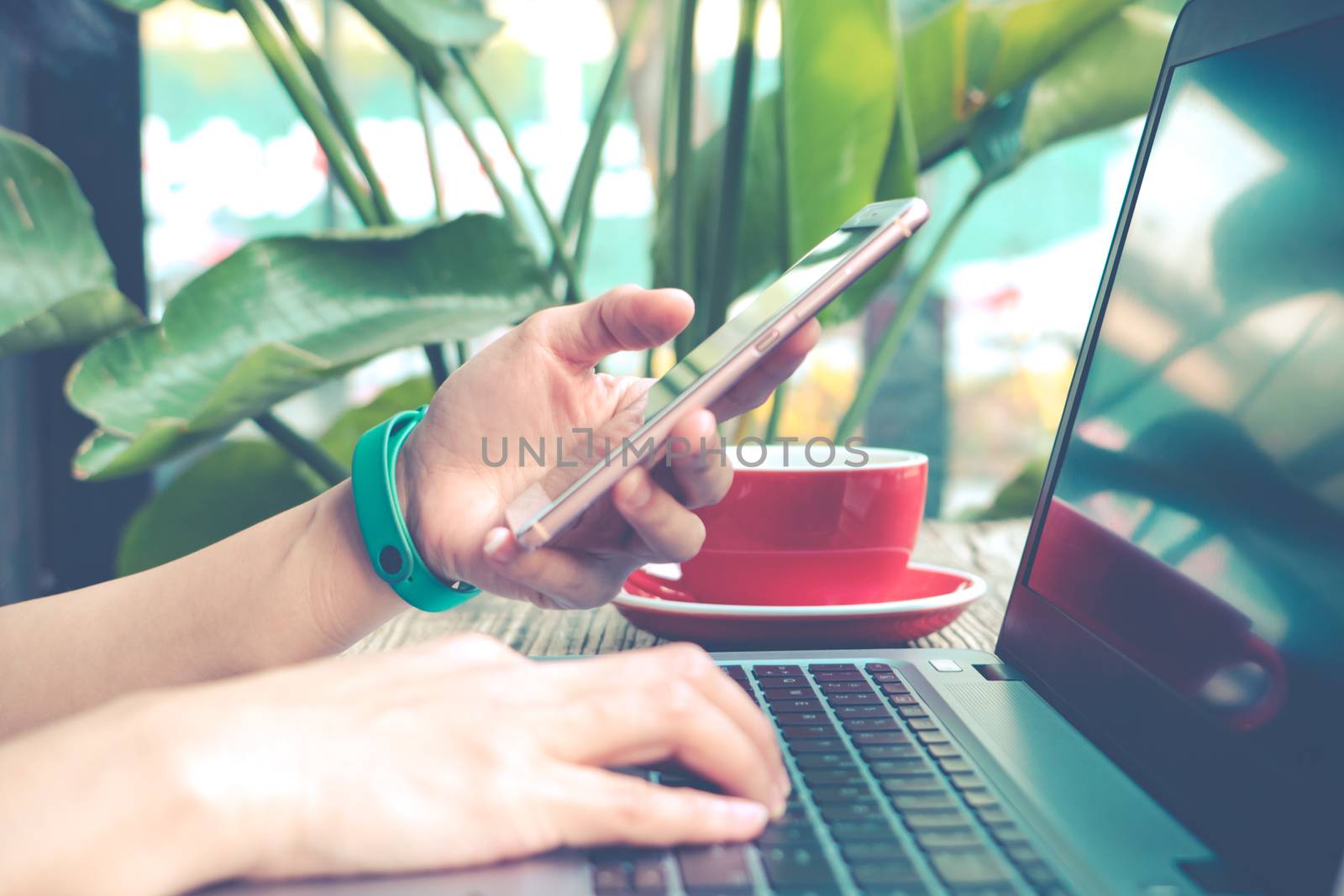 woman hand hold the smart mobile phone while using the laptop by psodaz