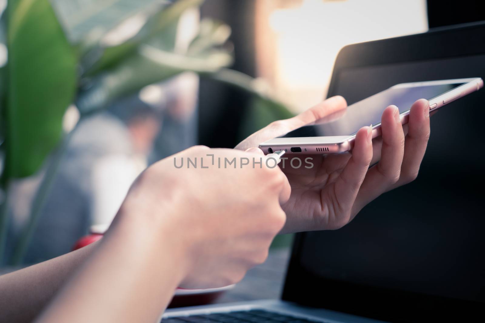 woman hand hold the charging cable plugging the smart mobile pho by psodaz