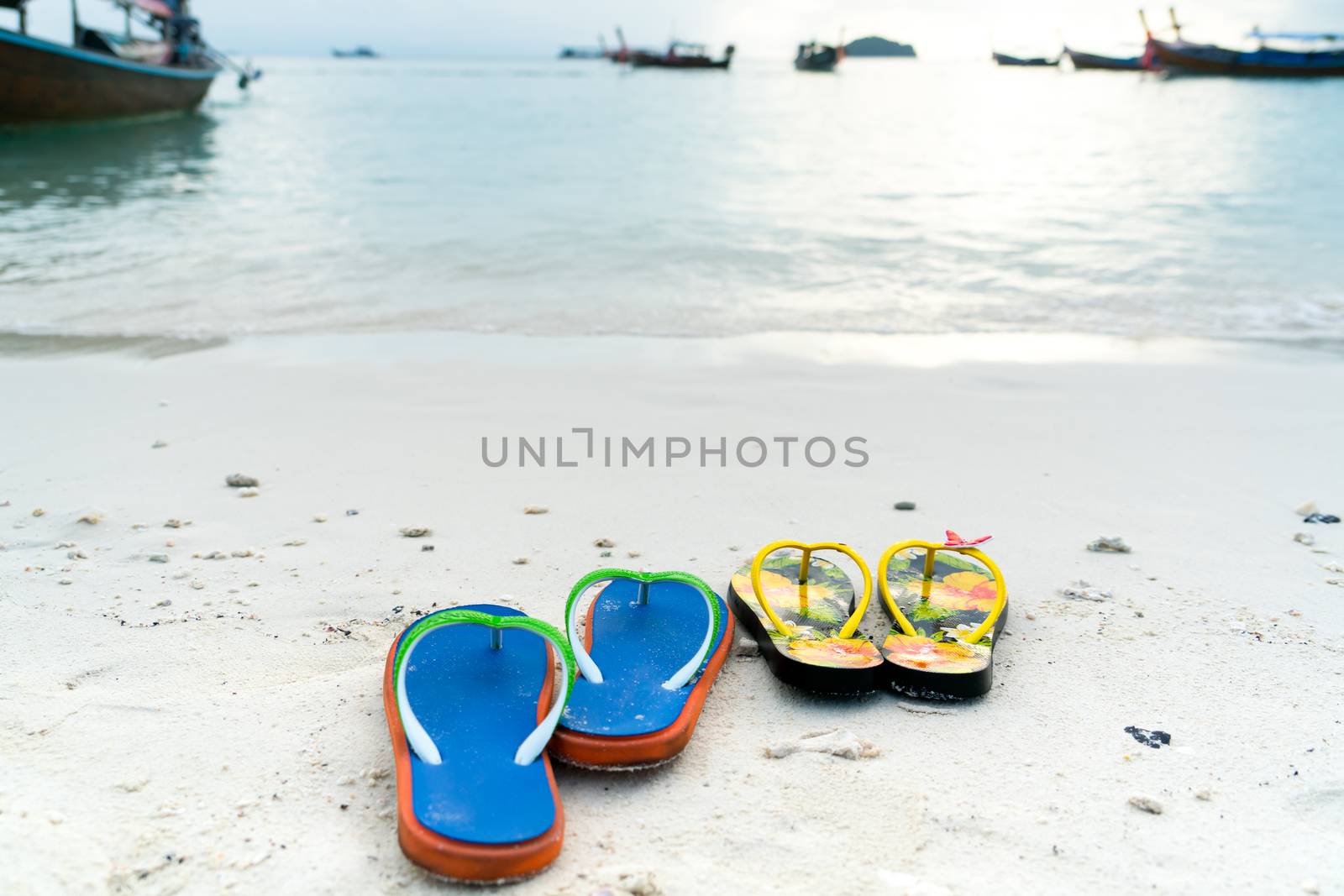 2 slippers on the white sand beach, travel and vacation time by psodaz