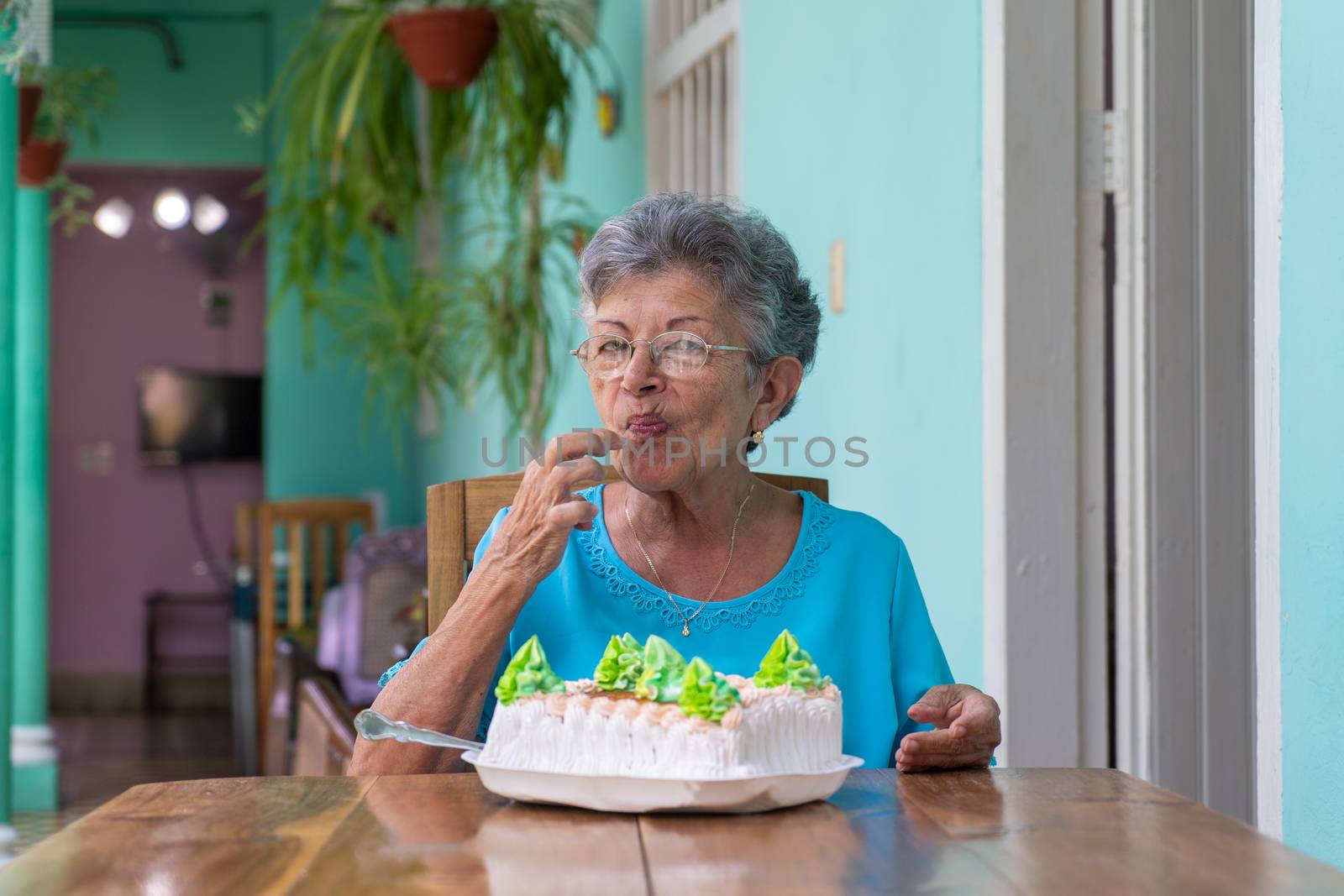 Elderly wrinkled woman sitting and a cake on table