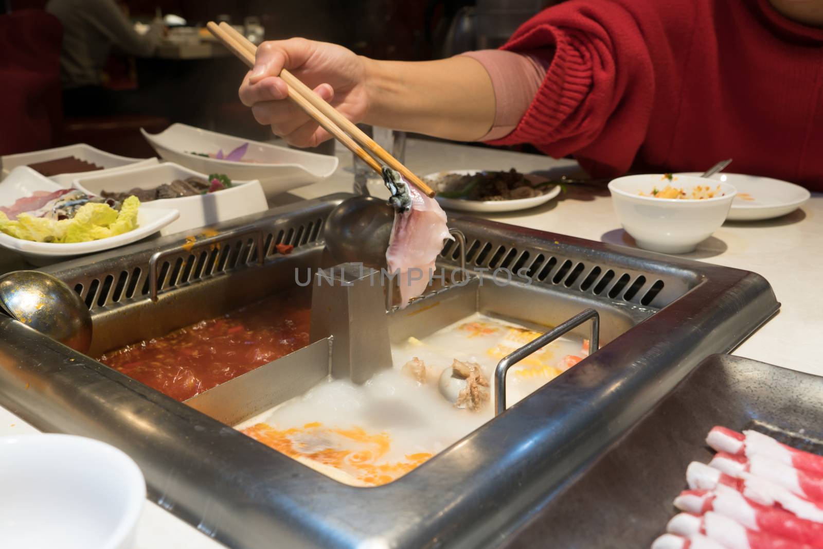 a red shirt women is cooking the Chinese shabu hotpot by psodaz