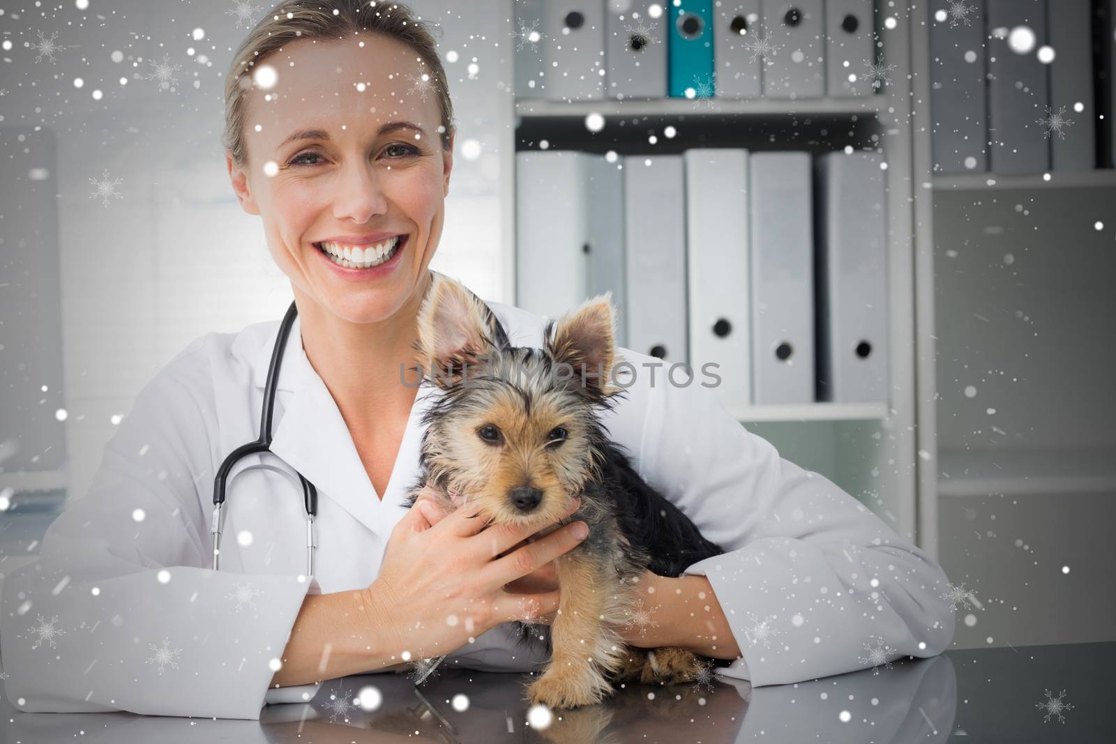 Happy female veterinarian holding puppy against snow