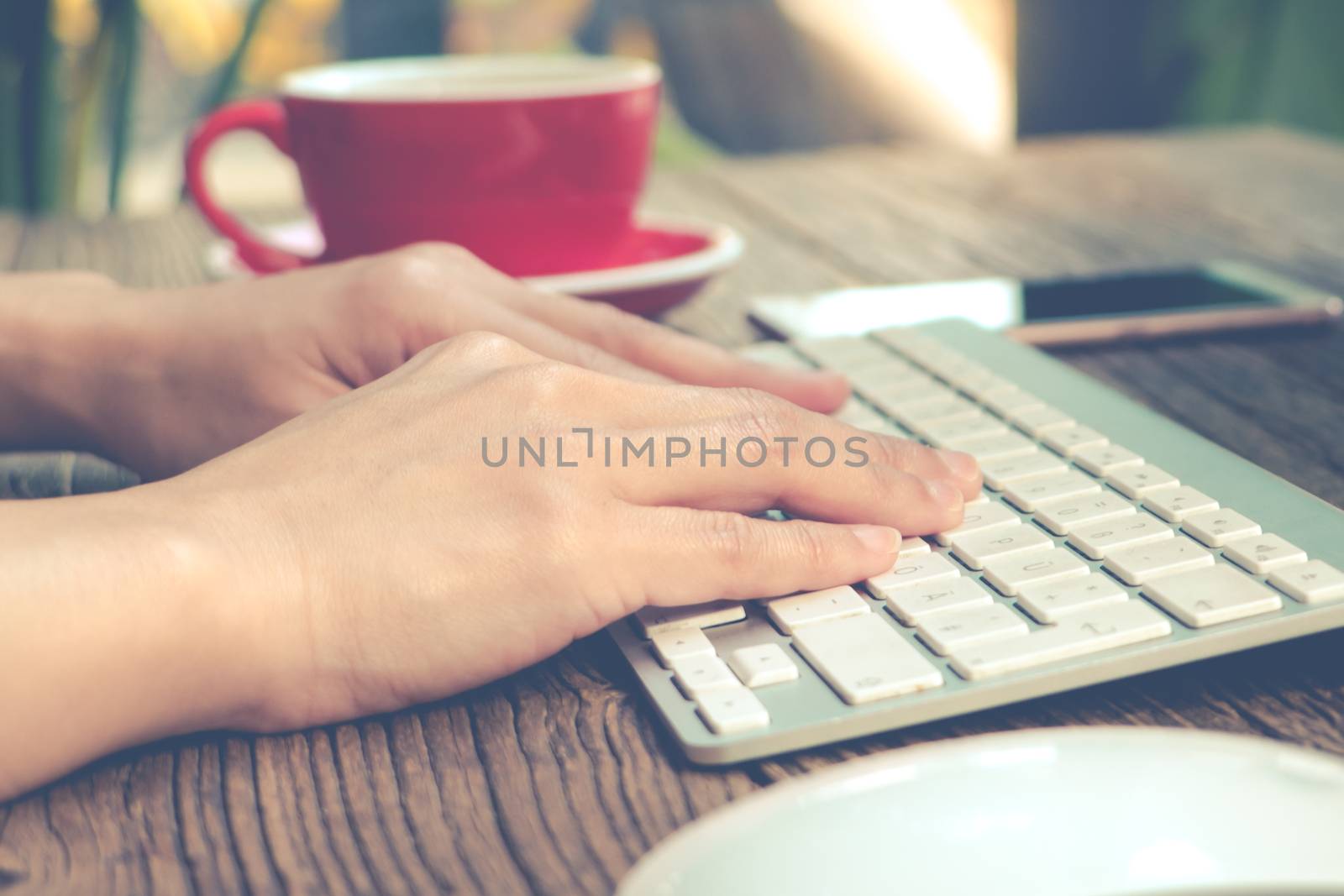 focus on the woman hand using laptop, searching, checking, browsing information at the coffee shop, matte and noise filter apply