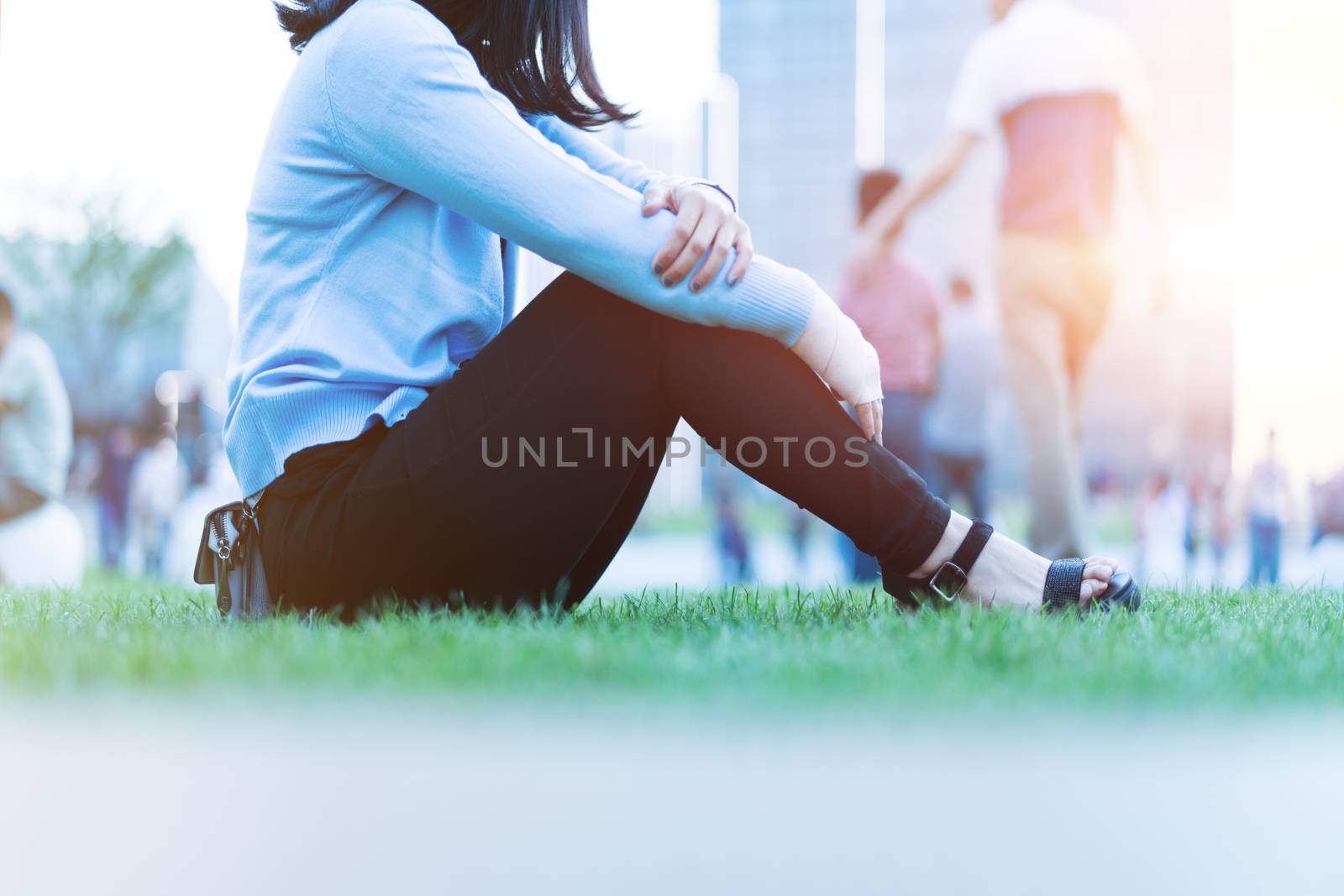 wrist hand pain women sit on the green grass in the playground on sunset, city lifestyle concept