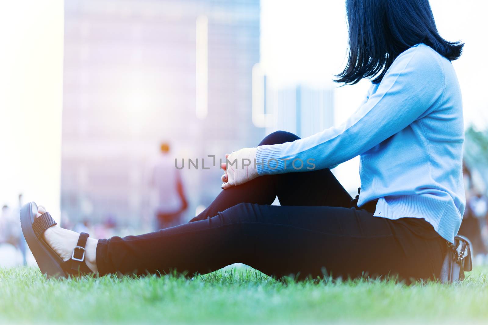 wrist hand pain women sit on the green grass in the playground on sunset, city lifestyle concept