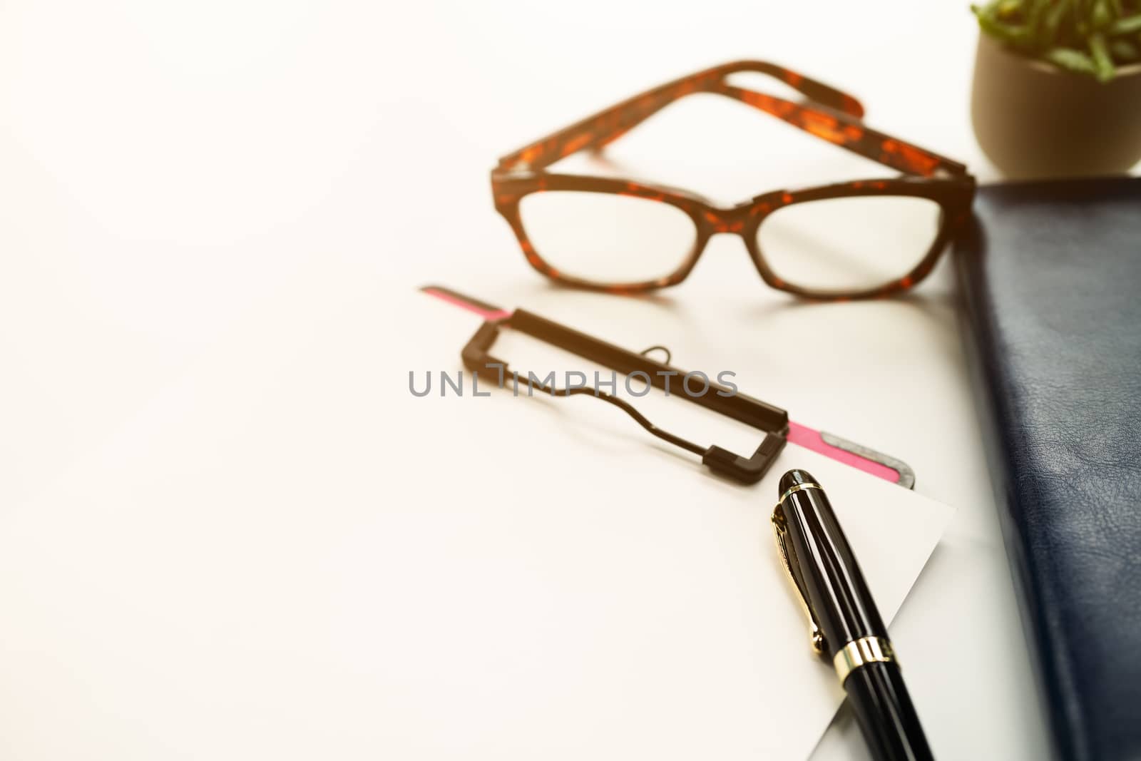 pen and clipboard with blank sheet, glasses on diary book on white background with copy space
