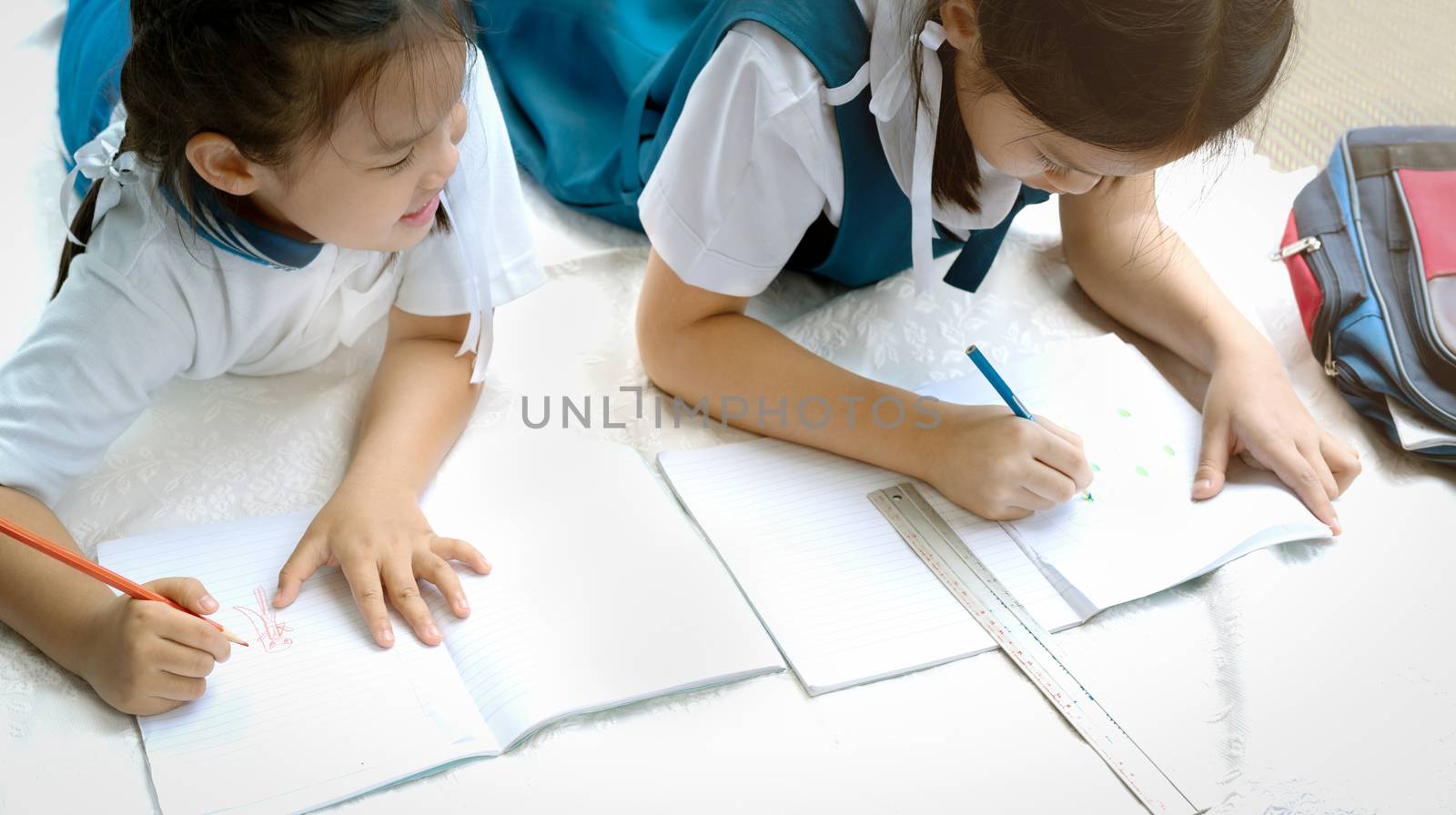 two sister girl writes a book. The decision of lessons. girl lay down drawing the picture