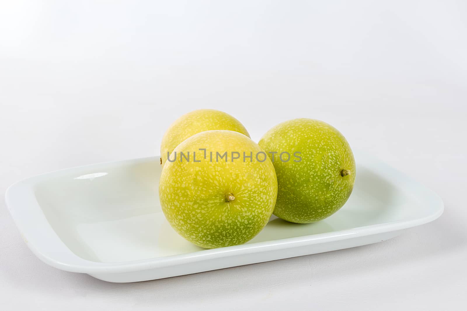 A group of three passion fruit in a bowl on a white background