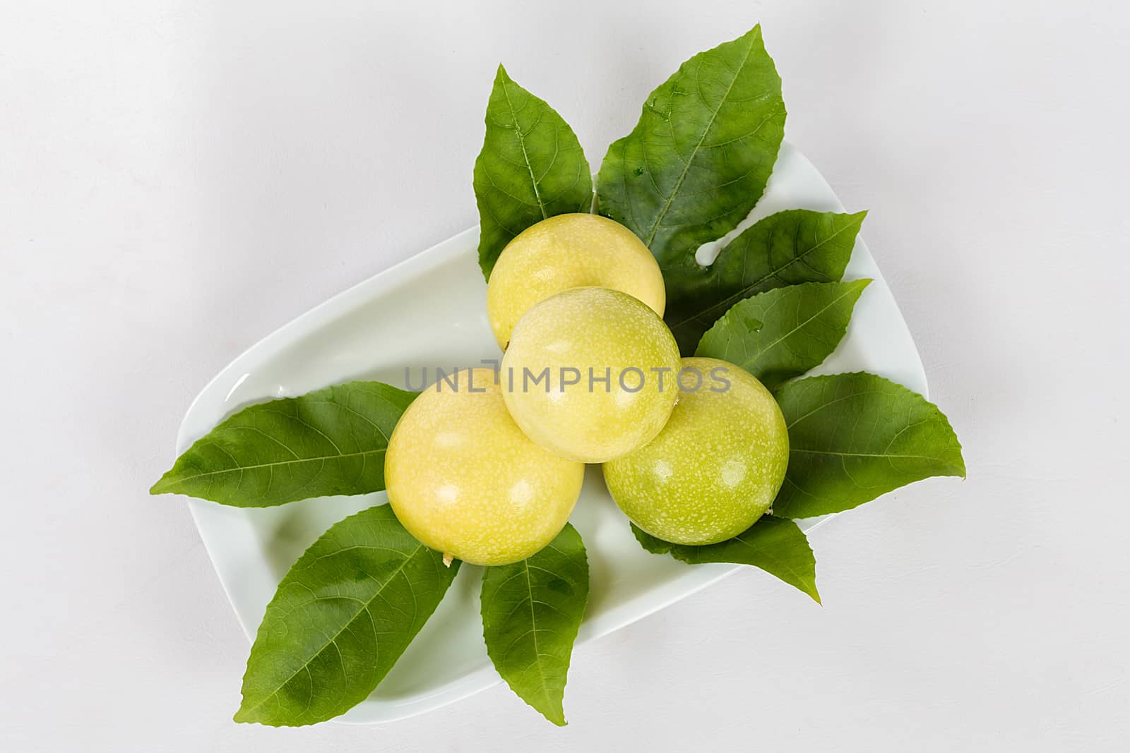 A group of four passion fruit in a bowl on a white background