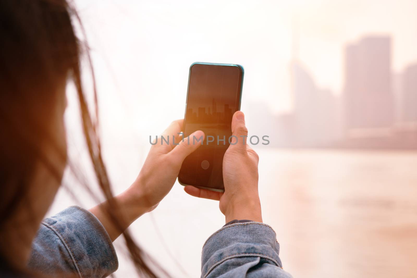 Cityscape on smartphone. View through the screen at Shanghai City on women screen, China.