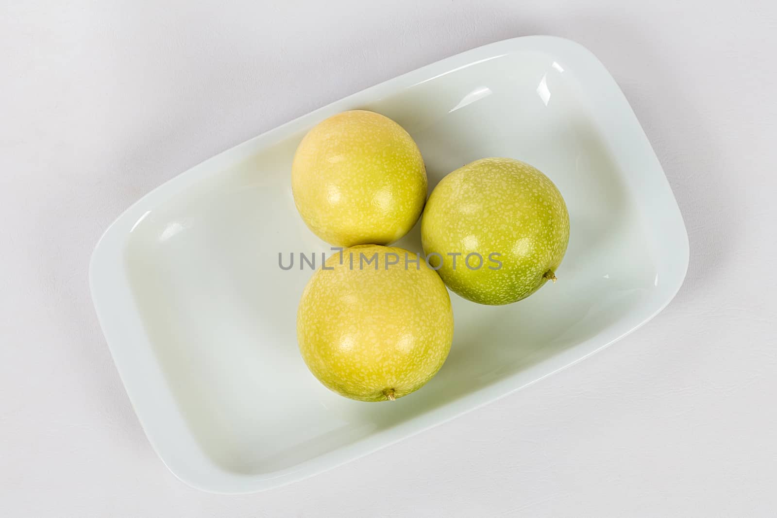 A group of three passion fruit in a bowl on a white background