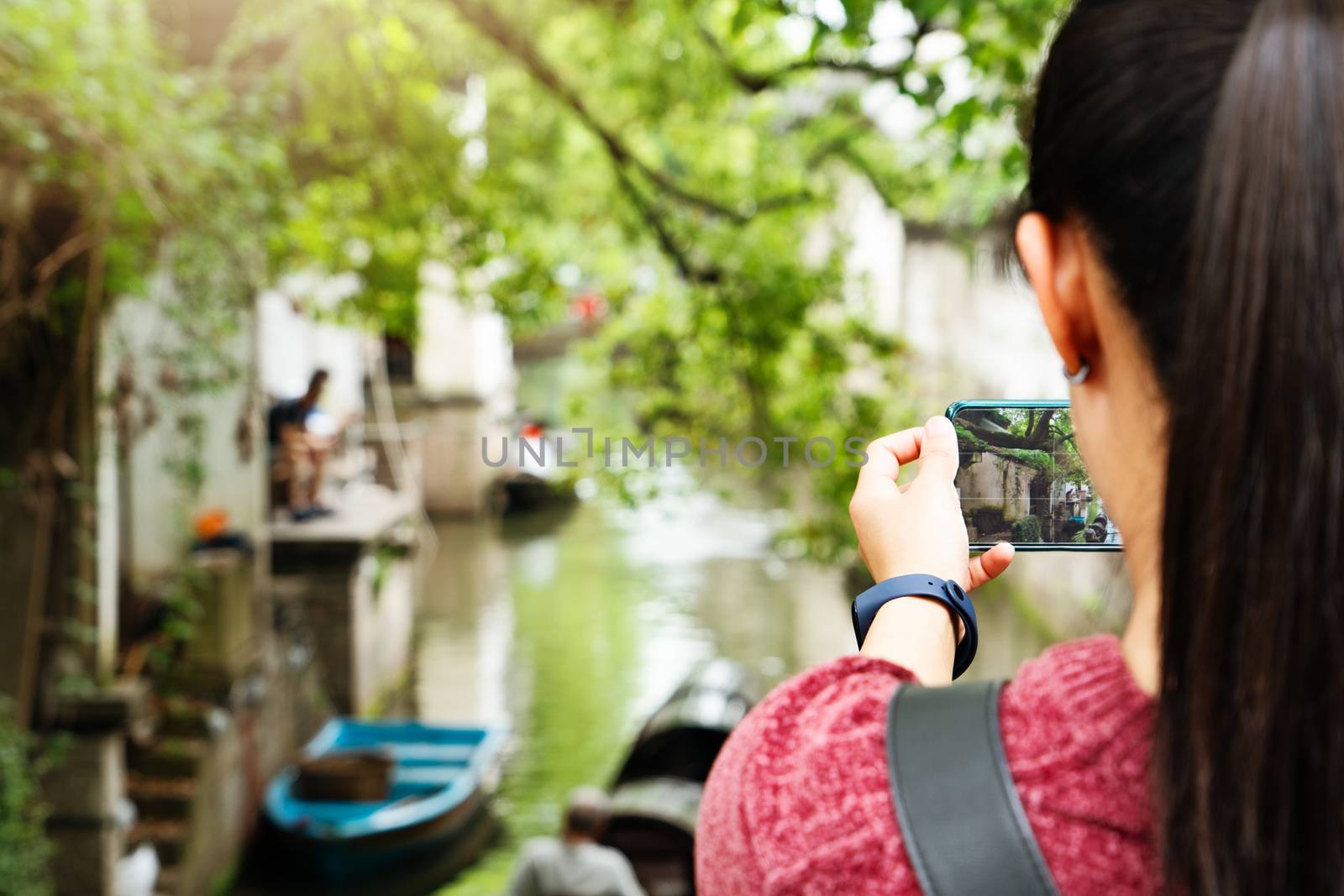 young woman having fun in local canal city in China with camera on smartphone making pictures